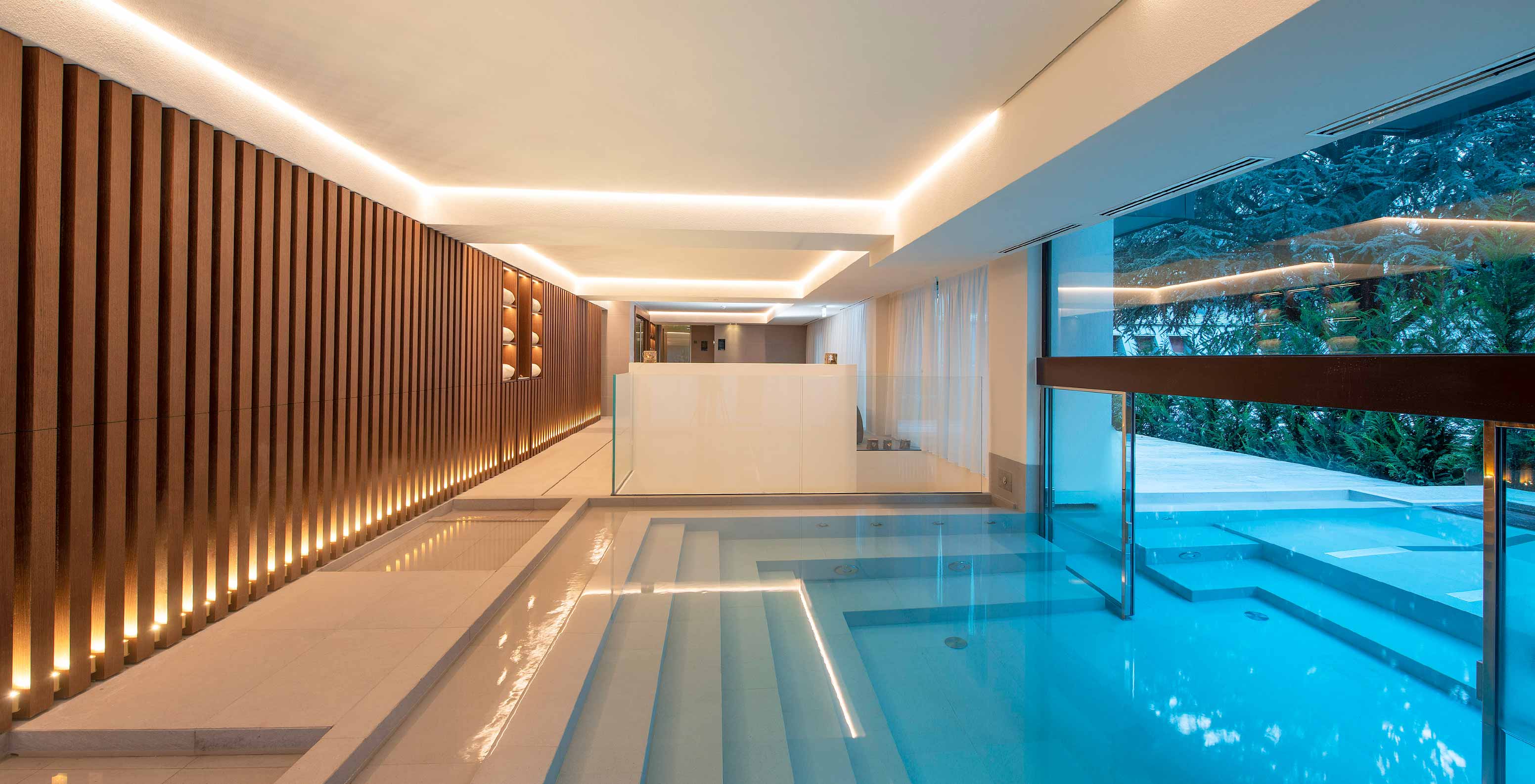 Piscina interior iluminada com luzes suaves e vista para o exterior no Le Massif Courmayeur, Hotel nos Alpes Italianos