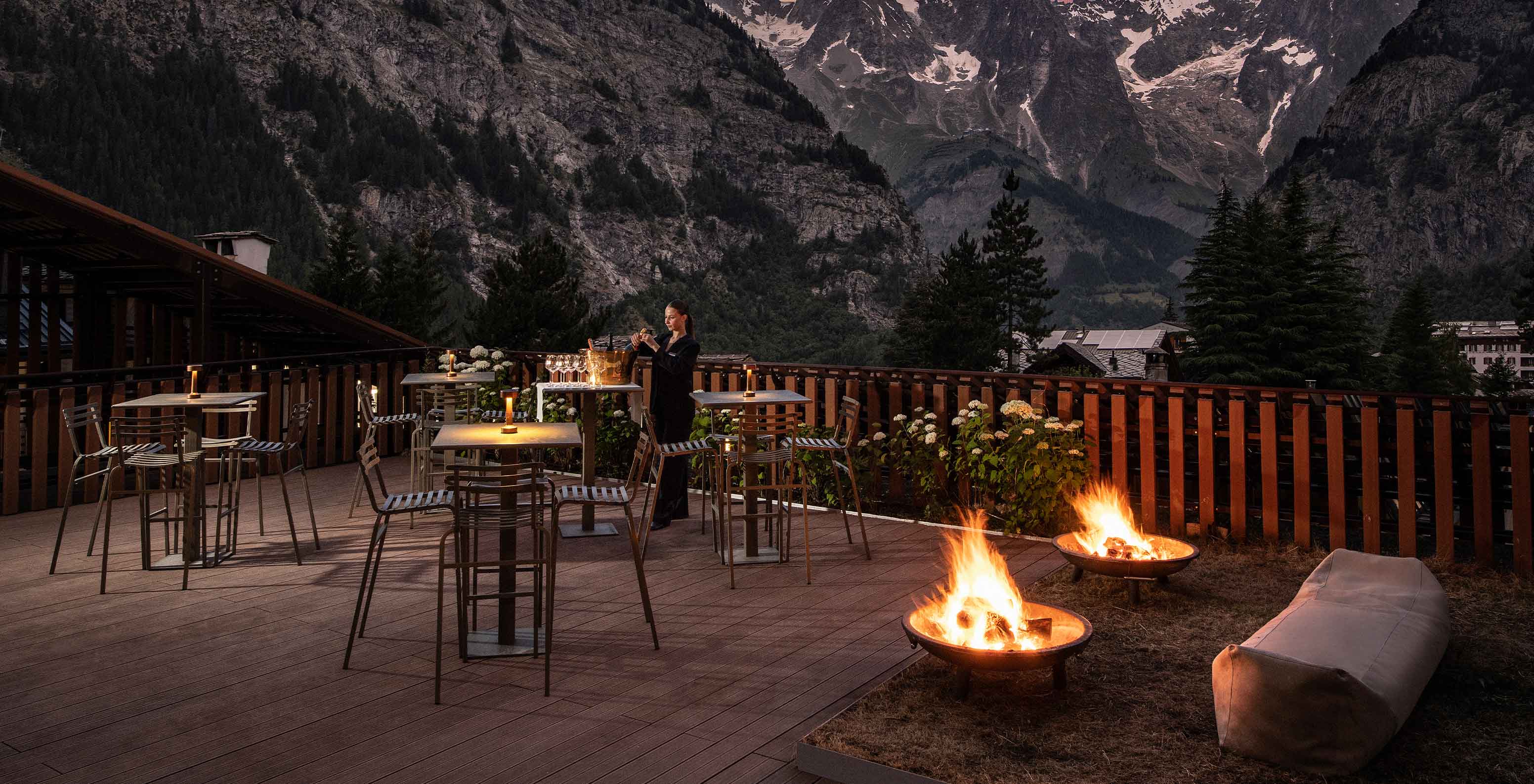 Terraço iluminado à noite no Le Massif Courmayeur, Hotel nos Alpes Italianos em Courmayeur para fazer ski, com mesas e fogueiras
