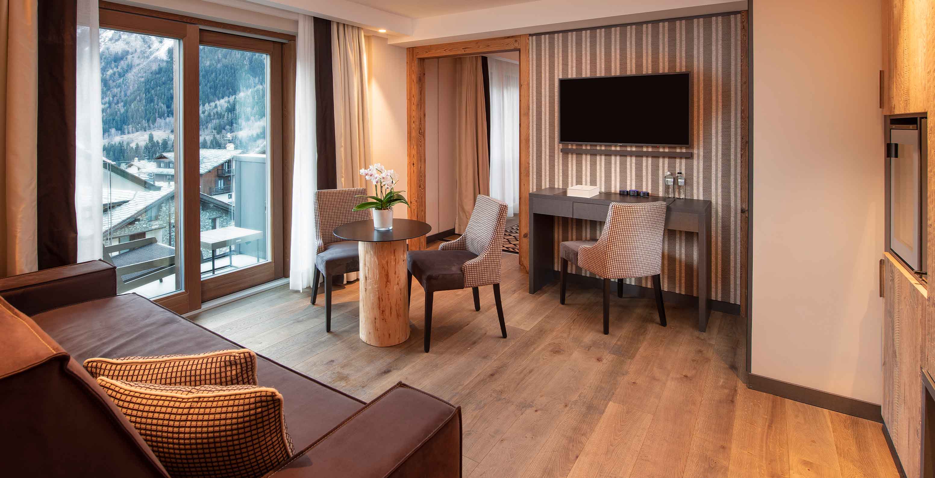 Sala de estar do Le Massif Courmayeur Hotel nos Alpes Italianos, com sofá, mesa redonda e vista para montanhas nevadas