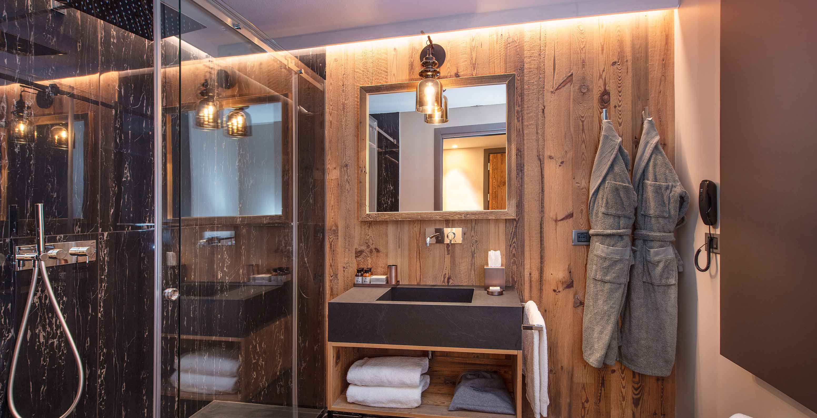 Casa de banho moderna no Le Massif Courmayeur, Hotel nos Alpes Italianos, com duche em vidro e lavatório em pedra