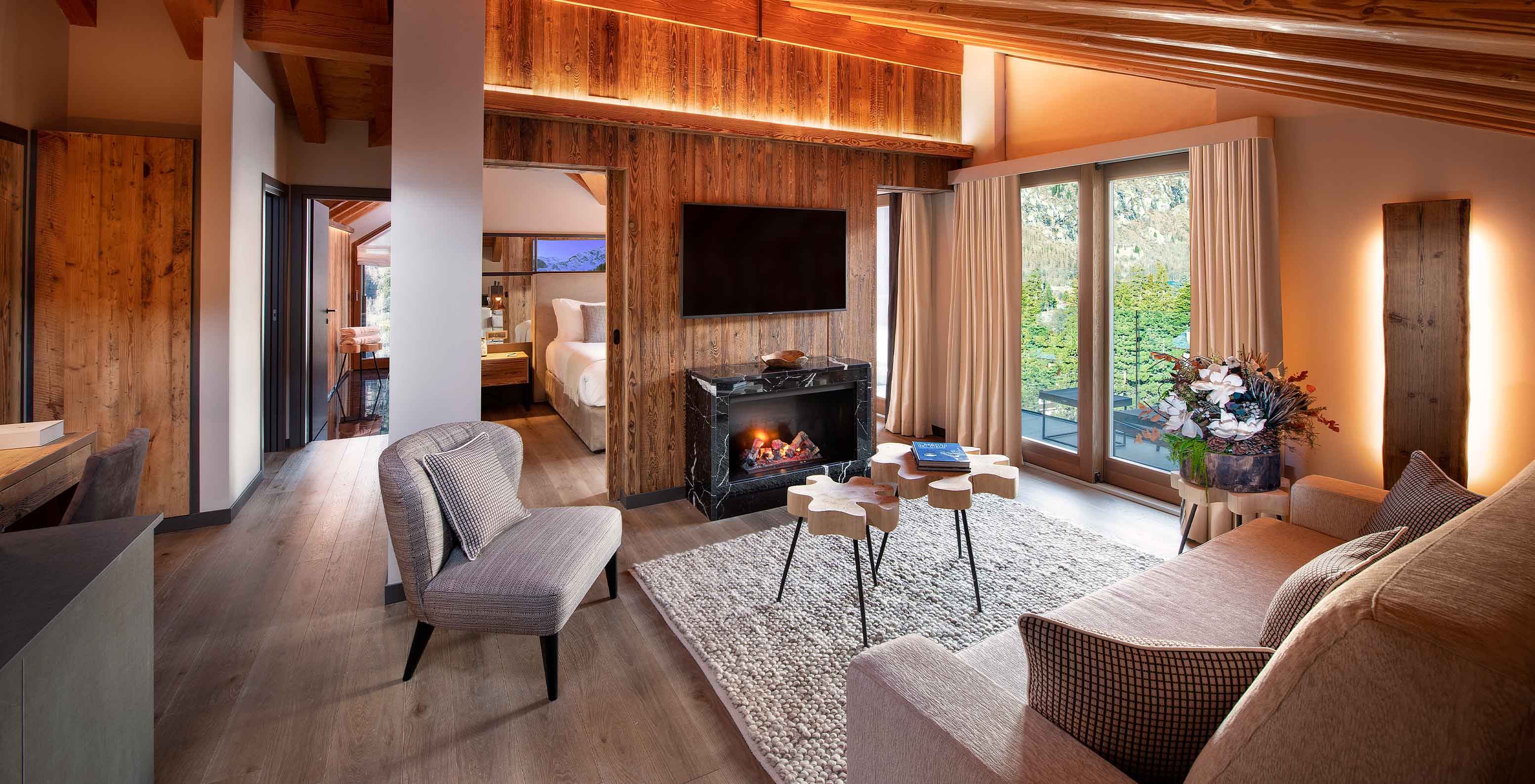 Sala do Le Massif Courmayeur Hotel nos Alpes Italianos com sofá, lareira acesa e vista para as montanhas