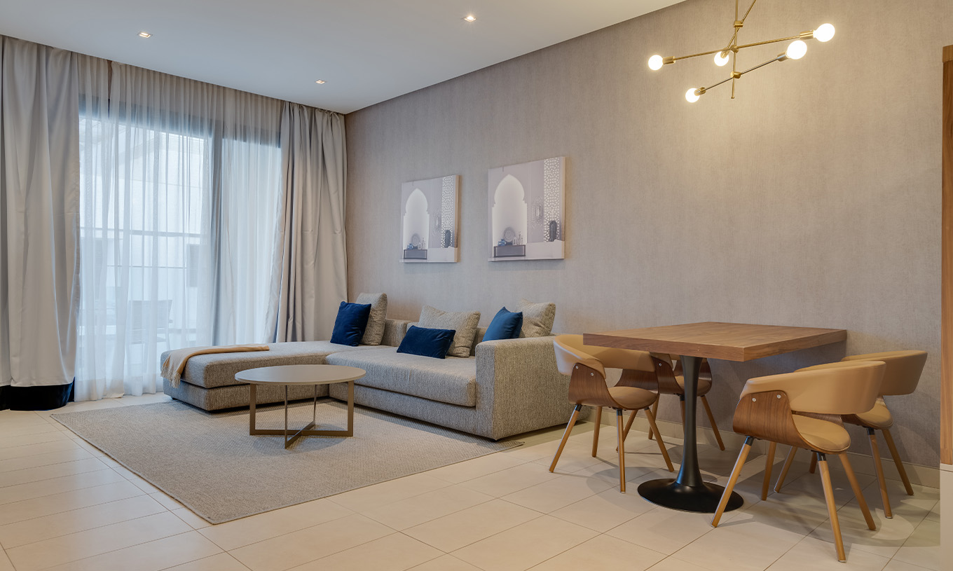 A Suite Familiar Premium do Pestana Casablanca tem um sofá cinzento grande com chaise longue ao lado da janela