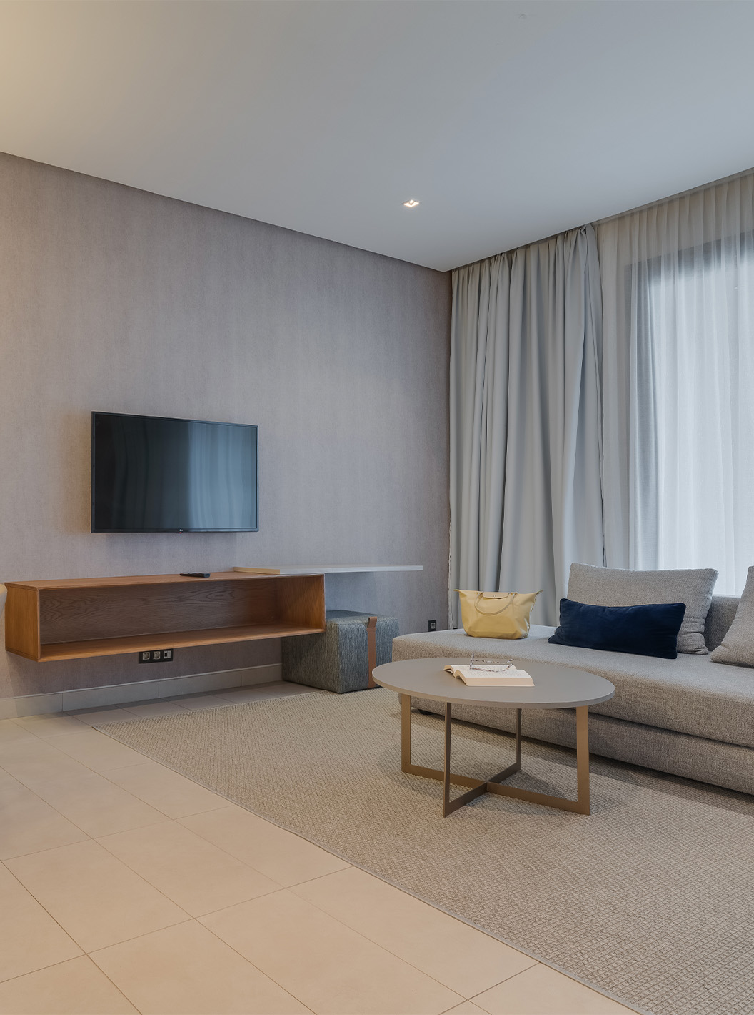 Suite Júnior no Pestana Casablanca com sala moderna, sofá cinzento, mesa de jantar e televisão mural
