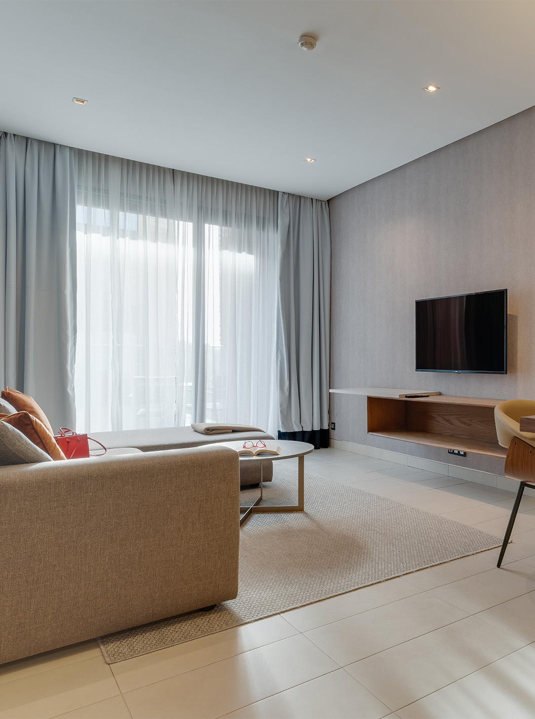 Suite no Pestana Casablanca com sala luminosa, mesa de trabalho, televisão e cortinas junto à varanda ampla