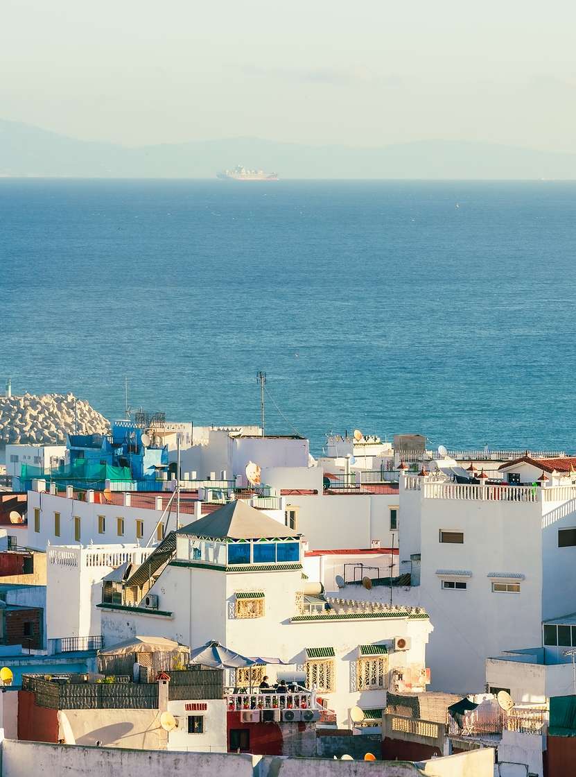 Vista da cidade de Tânger, Marrocos, com edifícios brancos de arquitetura tradicional marroquina e mar azul ao fundo