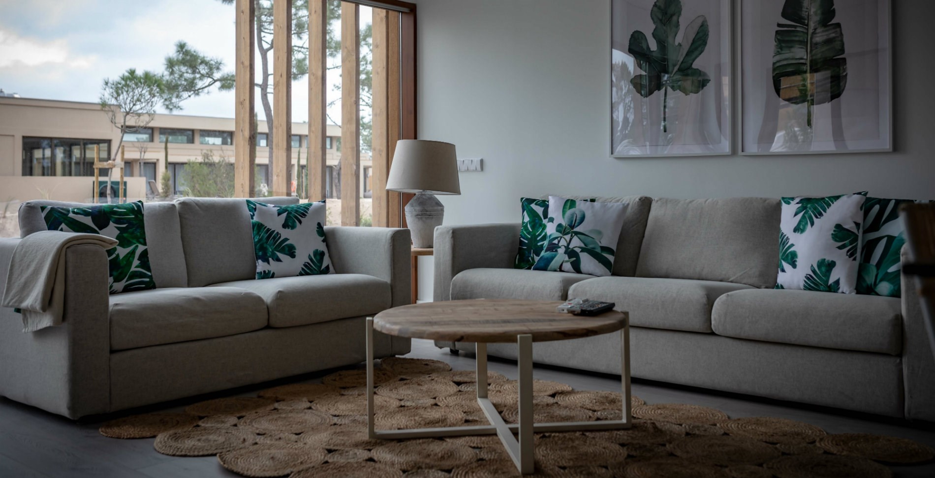 O Apartamento Eco Village Rés do Chão do Pestana Tróia Eco Resort tem uma sala com dois sofás, uma mesa e quadro de folhas
