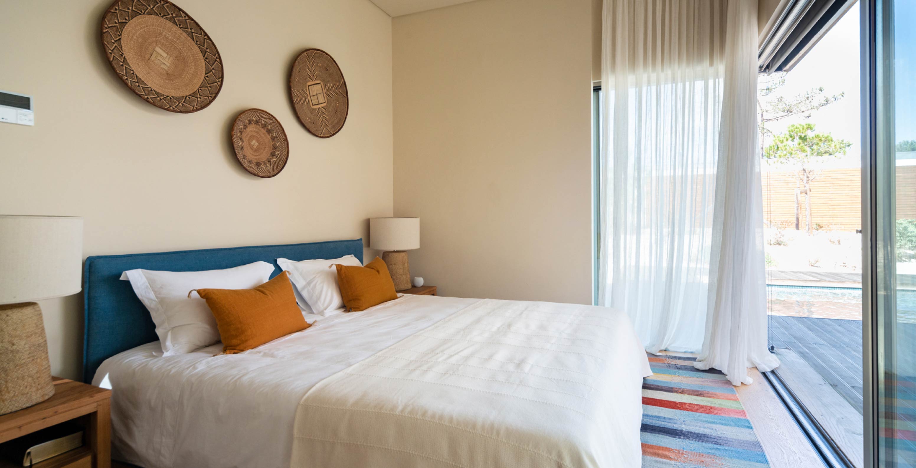 A Villa exclusiva com piscina do Pestana Tróia Eco Resort tem uma cama de casal com almofadas laranjas em frente a uma janela