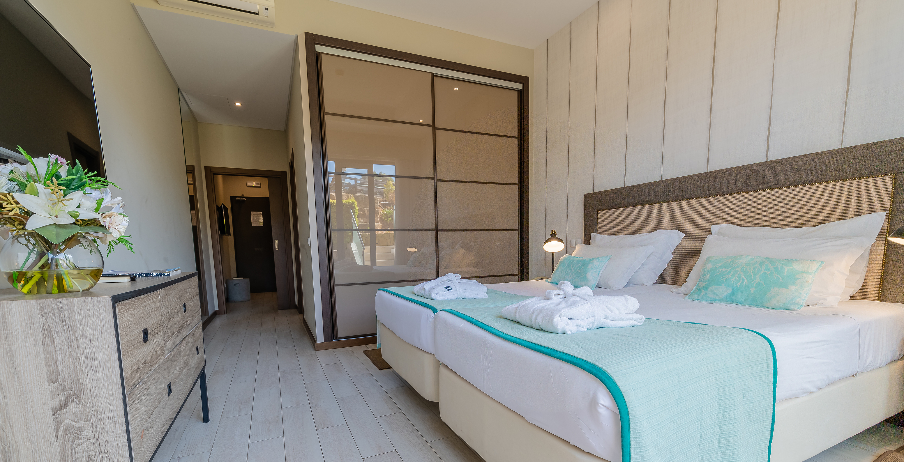 A Suite Garden do Pestana Alvor Park tem duas camas com cómoda de madeira, televisão e armário com portas de correr