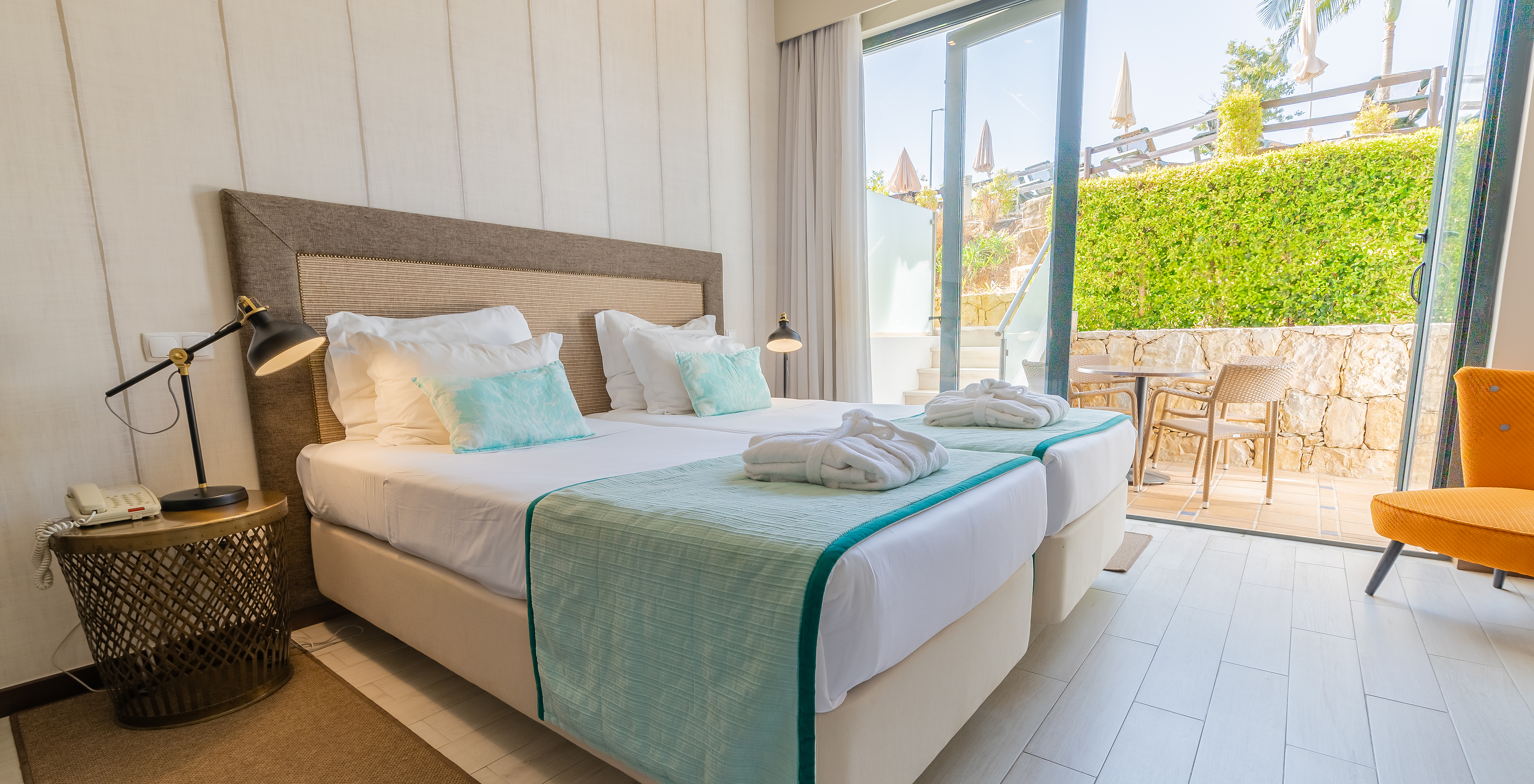 A Suite Garden do Pestana Alvor Park tem duas camas, cadeirão, cortinados e varanda com mesa e cadeiras