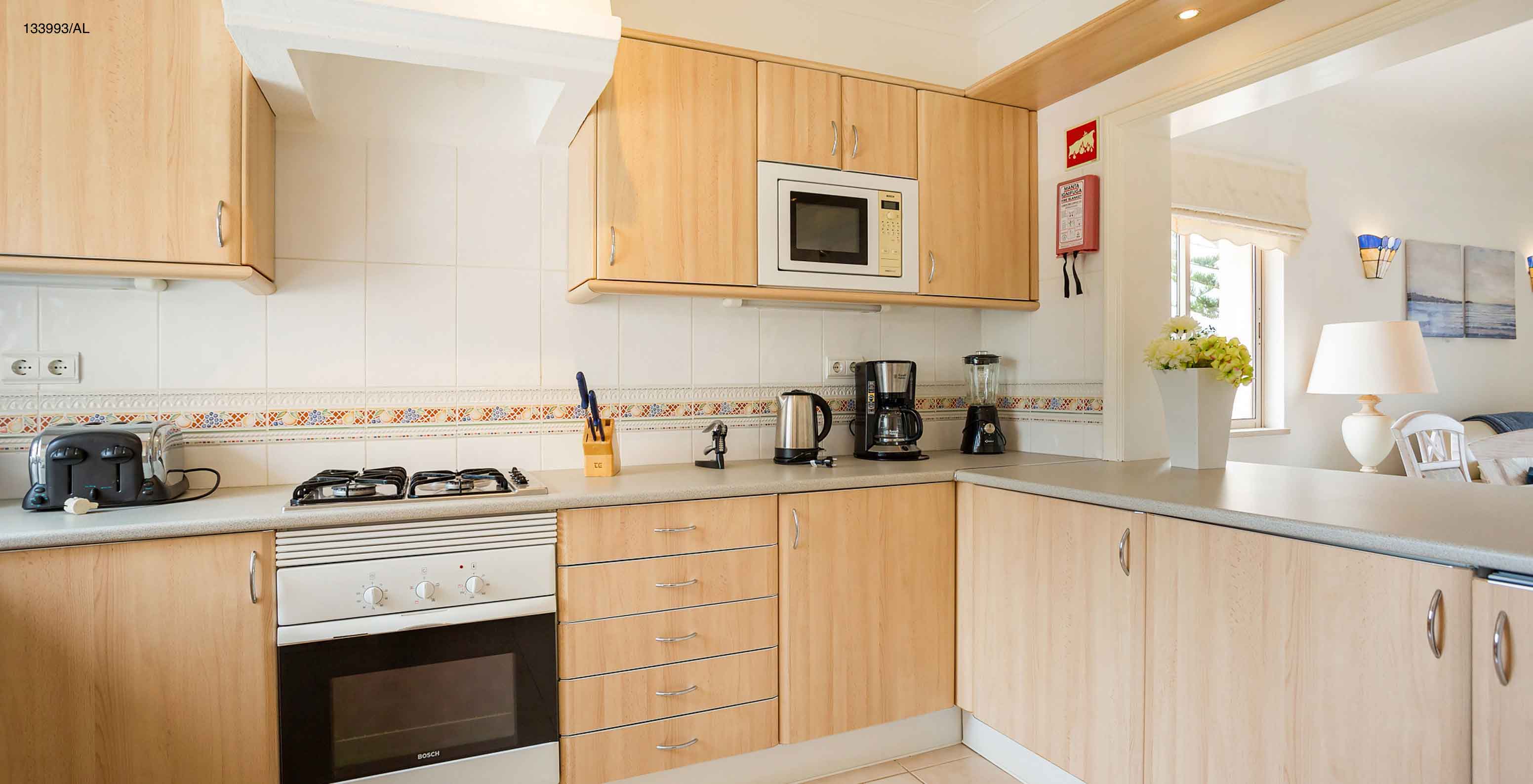 O Apartamento T2 Superior do Pestana Carvoeiro Golfe tem uma cozinha equipada com armários de madeira e eletrodomésticos