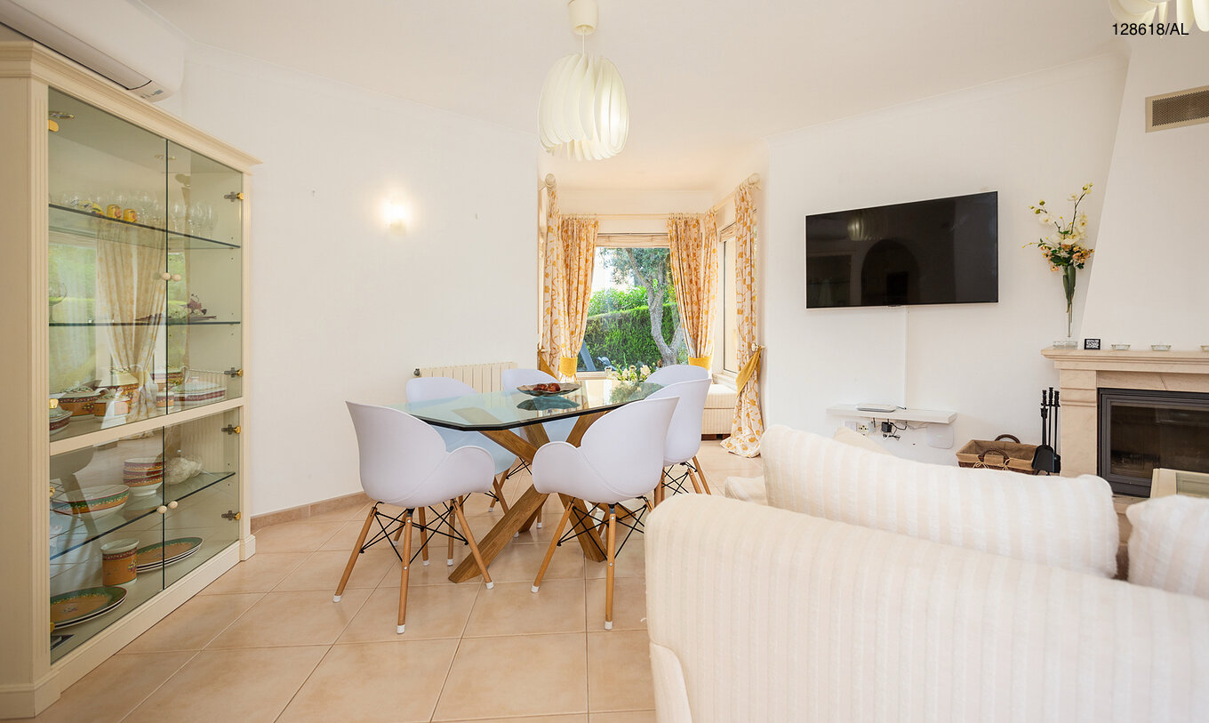 A Moradia V3 Superior do Pestana Carvoeiro Golfe tem uma sala de estar com uma mesa de vidro com cadeiras e uma televisão