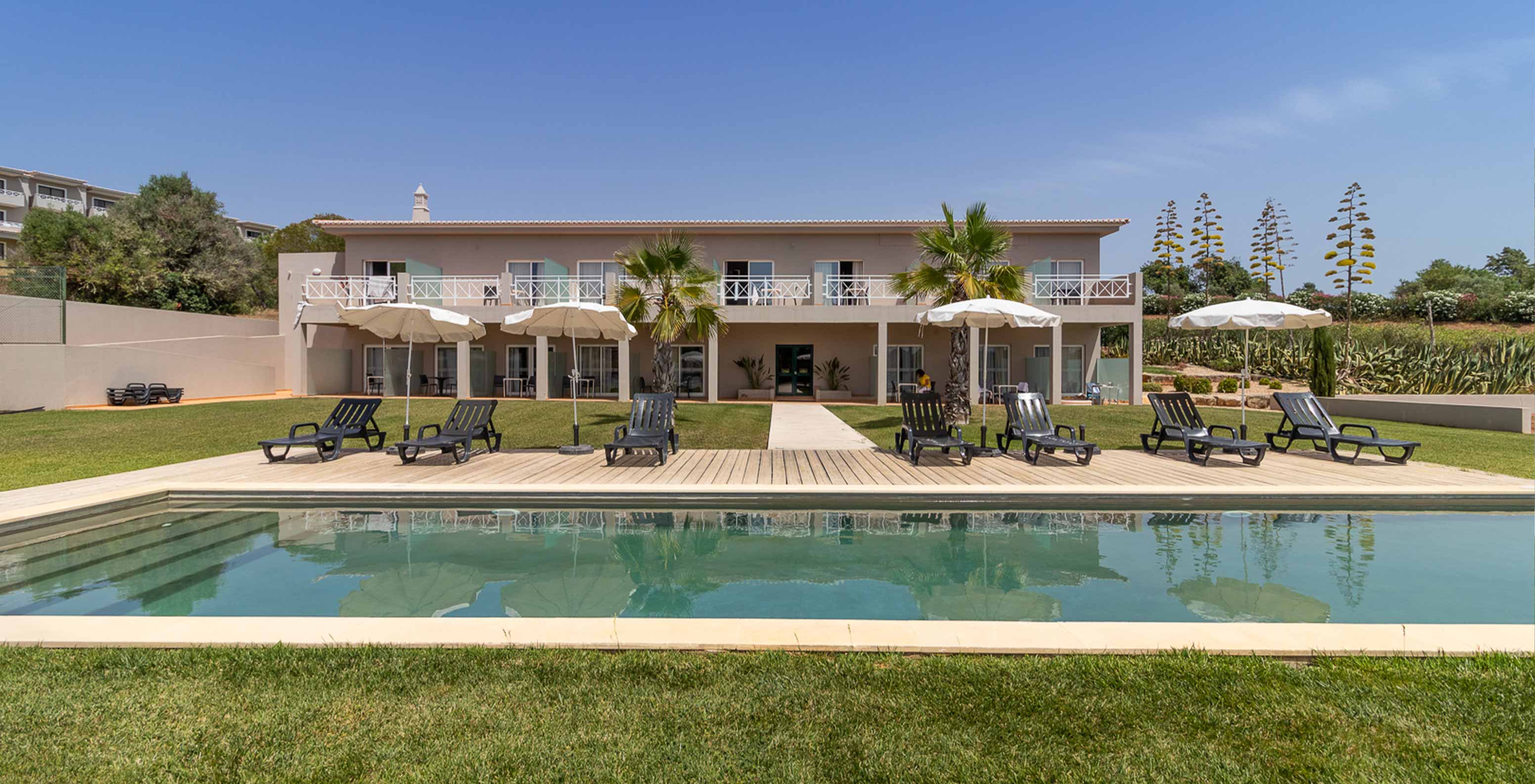 O Quarto Clássico do Pestana Gramacho Residences tem acesso à piscina, espreguiçadeiras e guarda-sóis em jardim cuidado