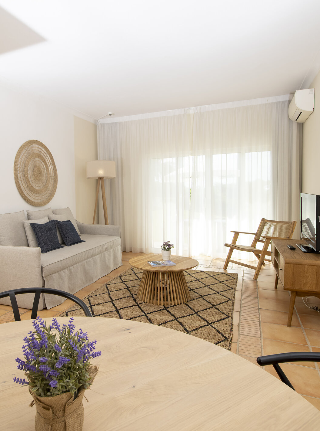 O Apartamento T2 Superior do Pestana Palm Gardens tem uma sala com uma mesa redonda, sofá, televisão e janela para o jardim