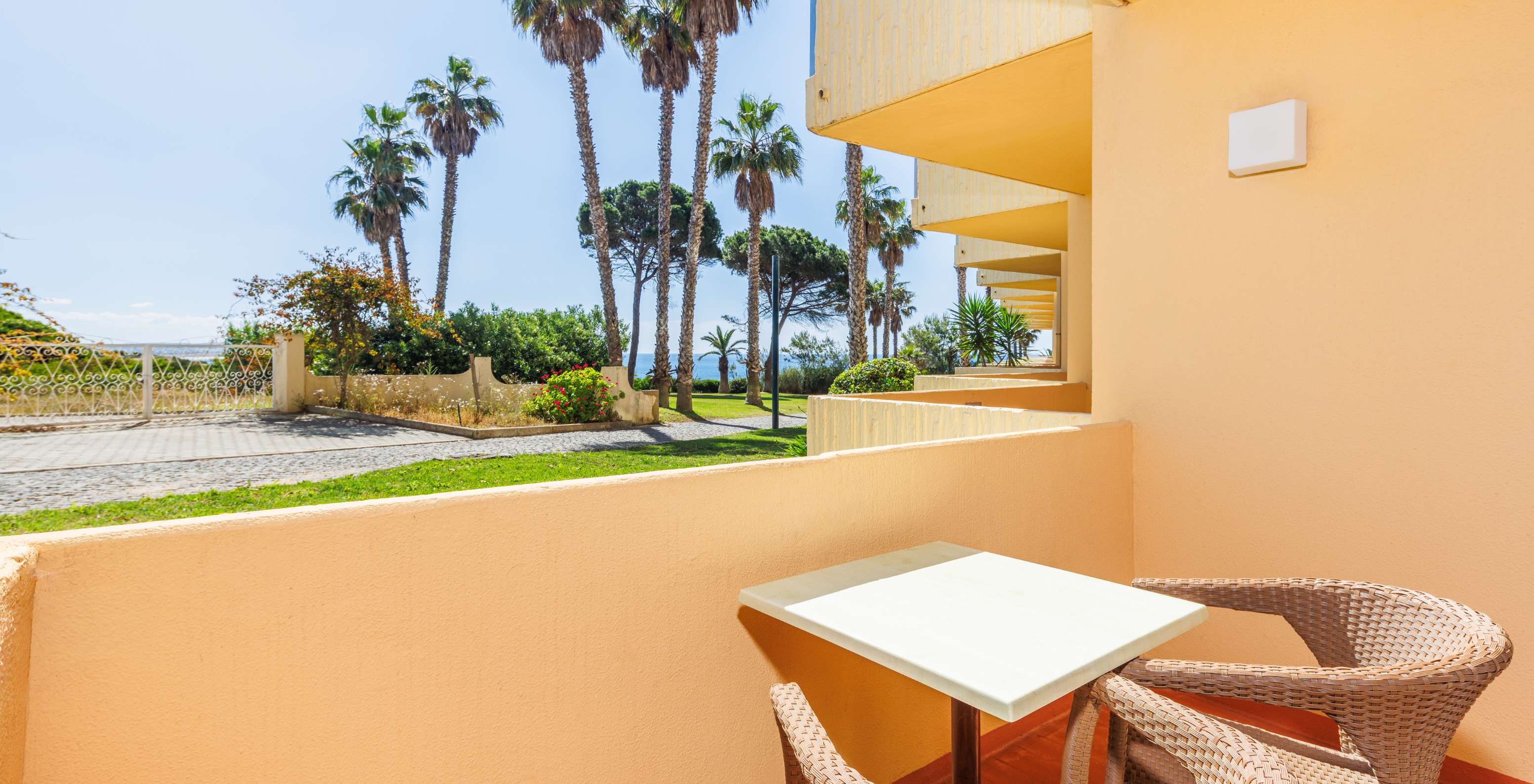 Quarto Deluxe com Vista Jardim e Varanda no Pestana Viking, com terraço mobilado junto a palmeiras
