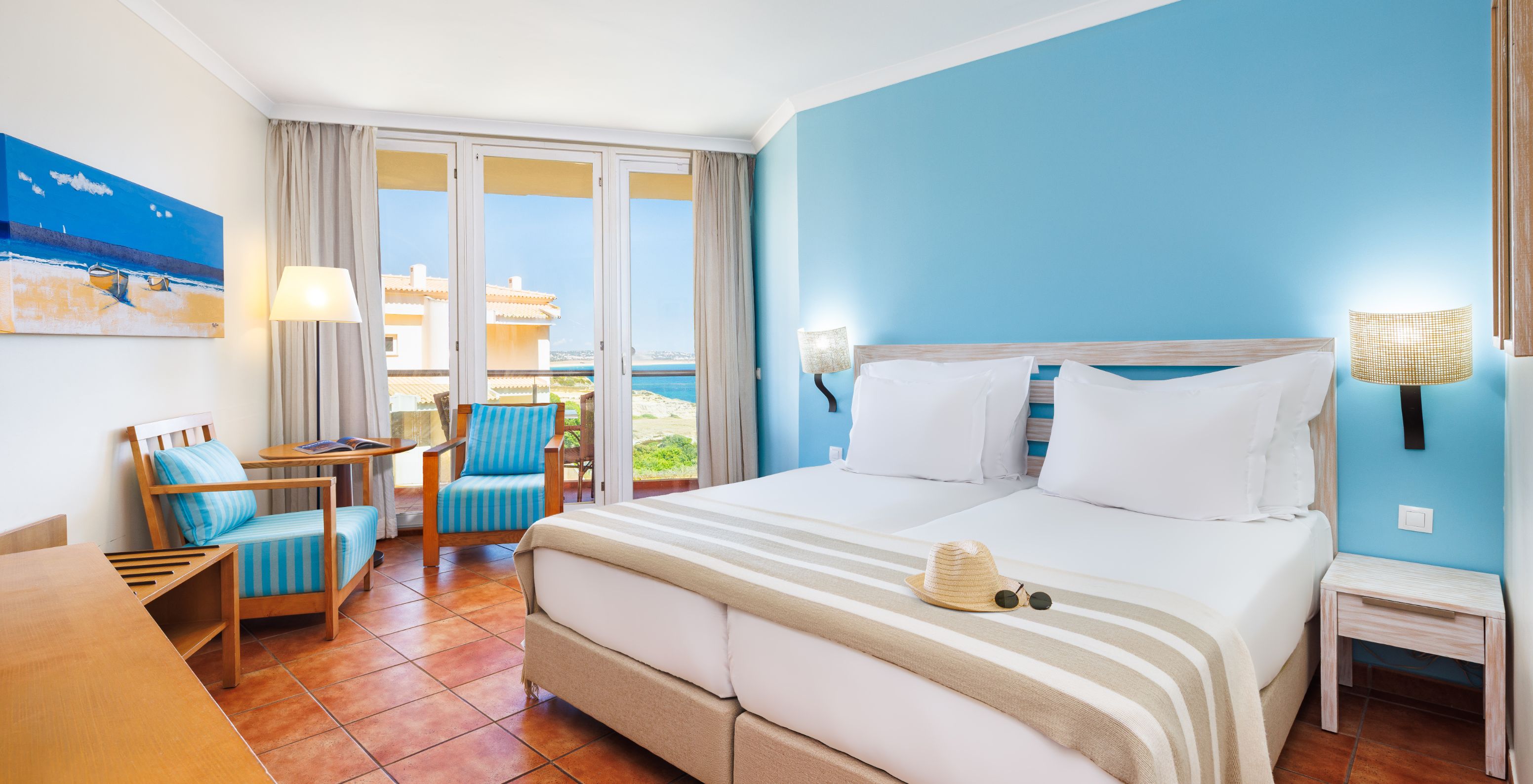 Quarto Deluxe Vista Mar do Pestana Viking com cama ampla, cadeirões junto à varanda e vista costeira