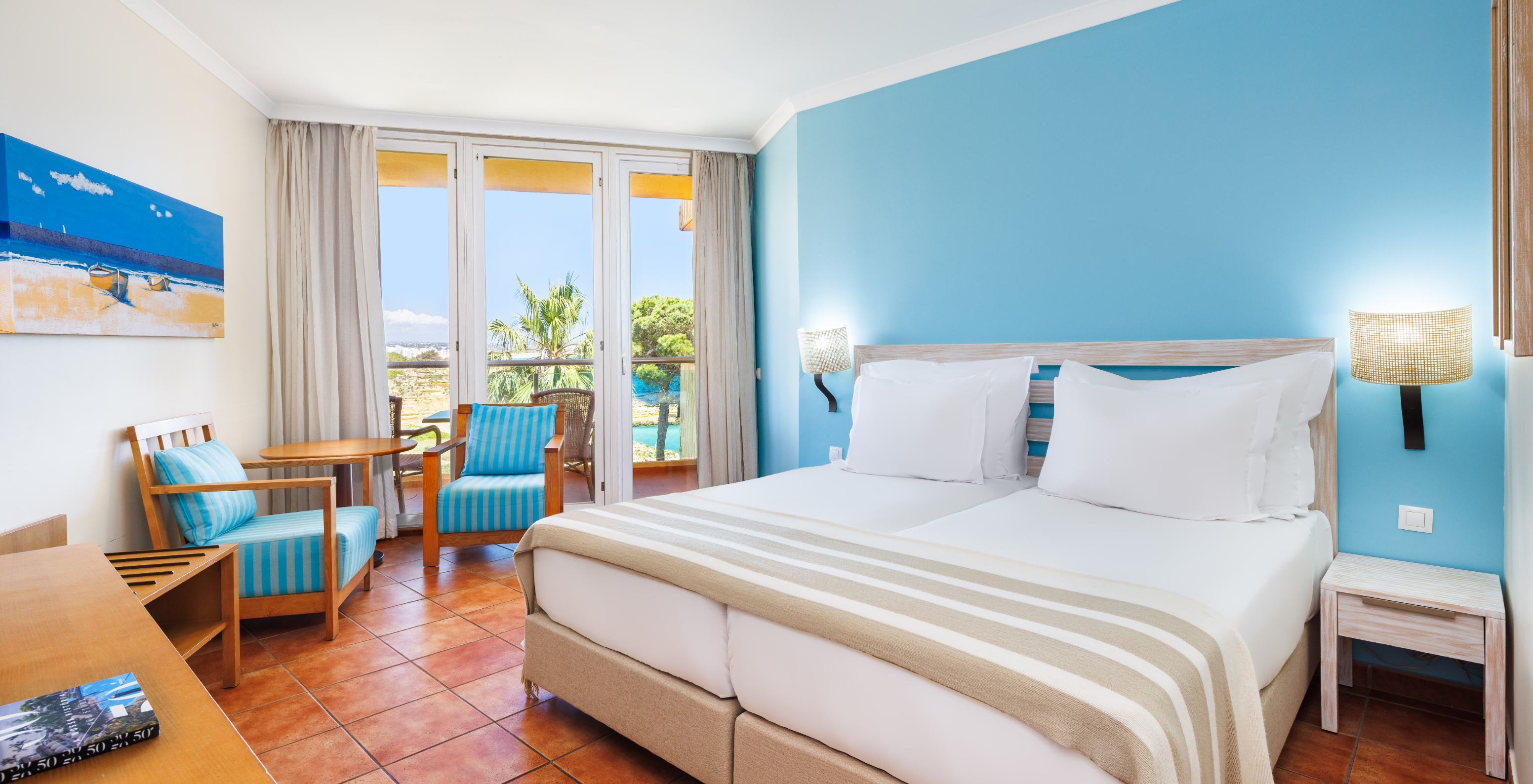 Quarto Deluxe com Vista Lateral Mar no Pestana Viking, com cama ampla e varanda voltada para o mar azul