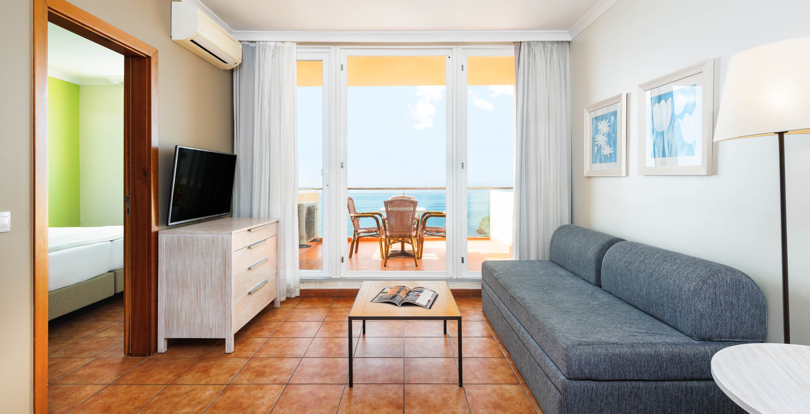 Pestana Viking Hotel com Piscina em Armação de Pêra, sala luminosa com sofá e varanda voltada para o mar