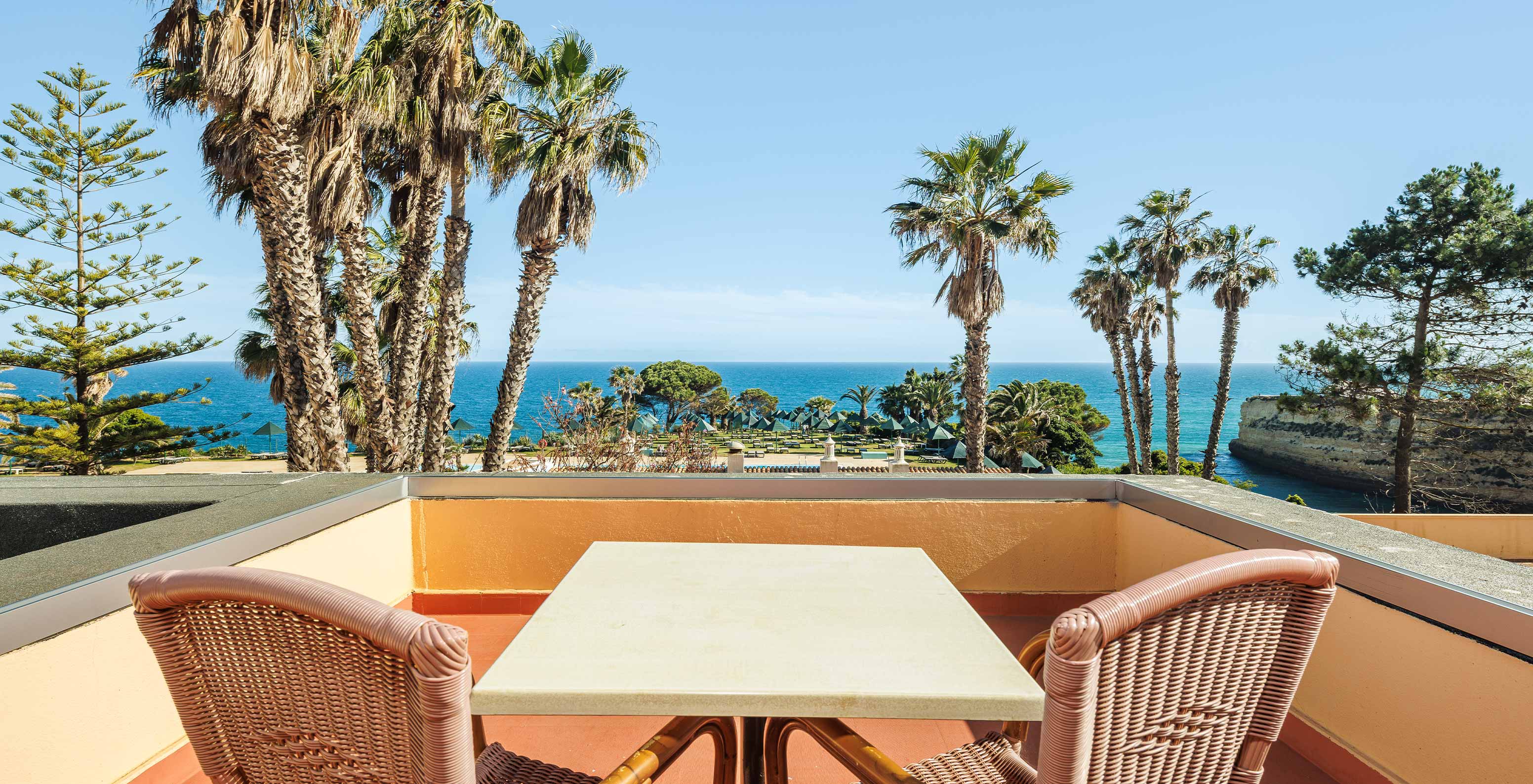 Suite T2 com varanda no Pestana Viking com terraço mobilado e vista para o mar entre palmeiras e falésias