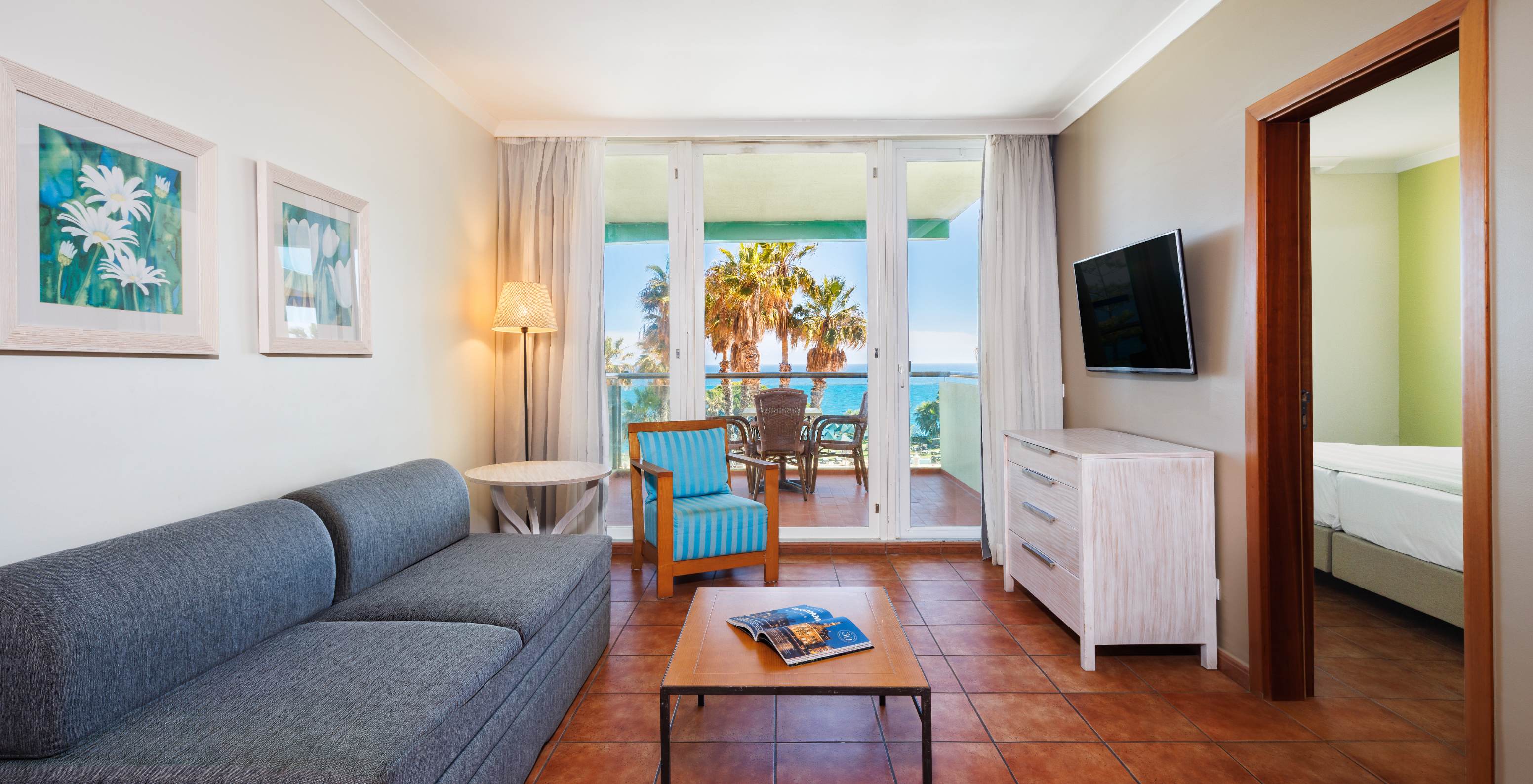 Suite Vista Mar no Pestana Viking com sala luminosa, sofá cinzento e varanda voltada para palmeiras e mar