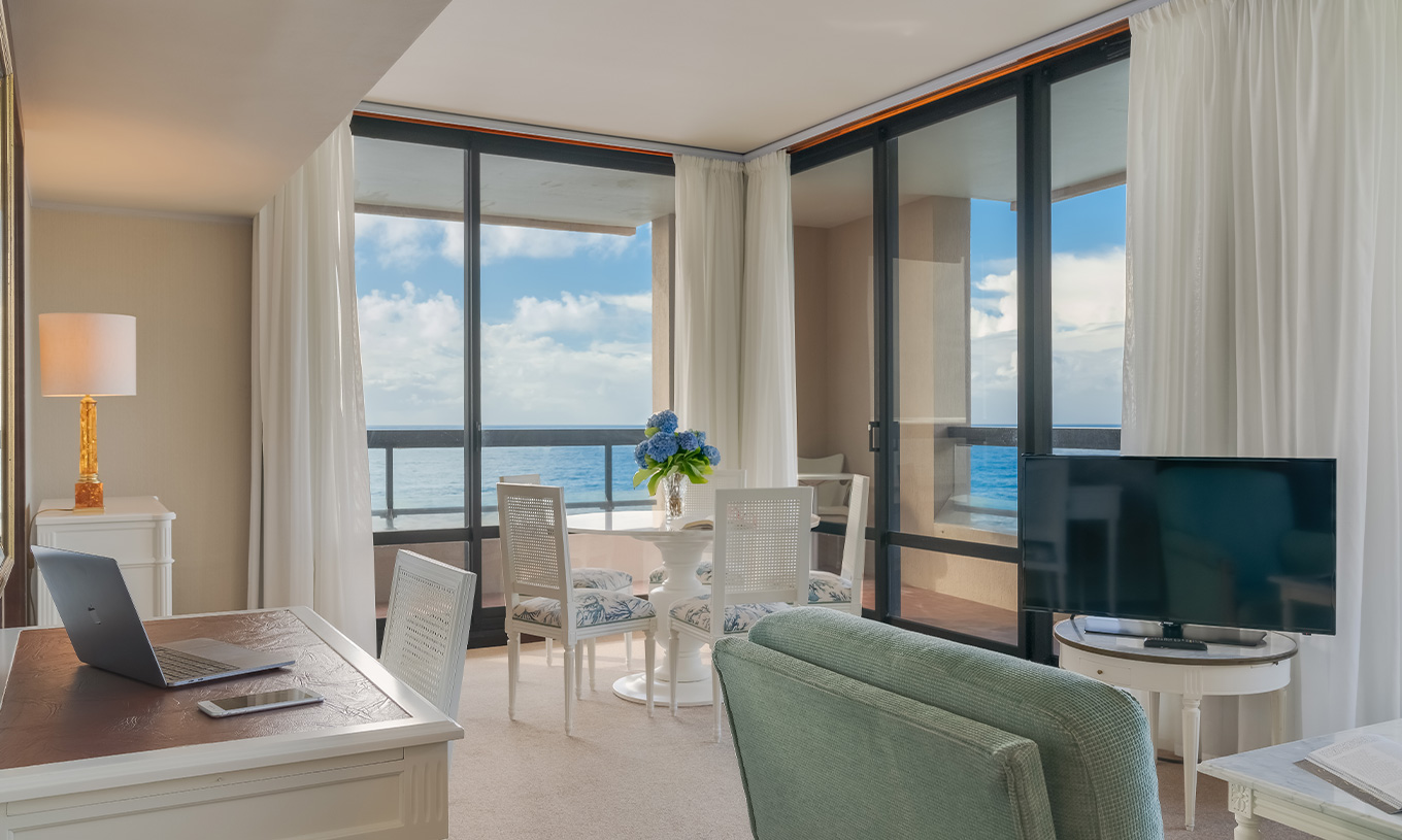 A Suite do Pestana Bahia Praia tem uma sala de estar com secretária, uma mesa e um sofá com televisão, com vista para o mar