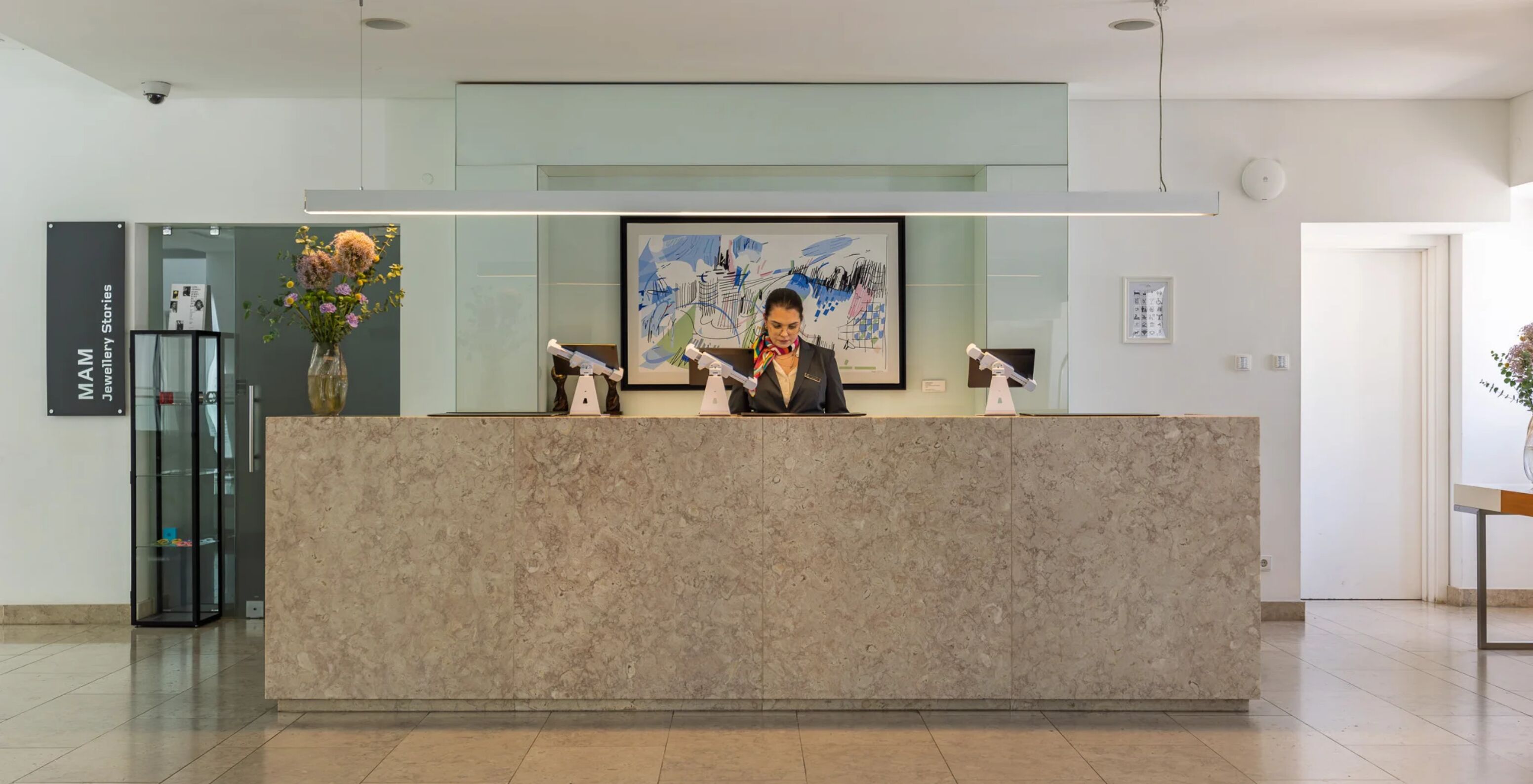 Hotel Pestana Cidadela Cascais com receção moderna em mármore e colaboradora ao balcão iluminado