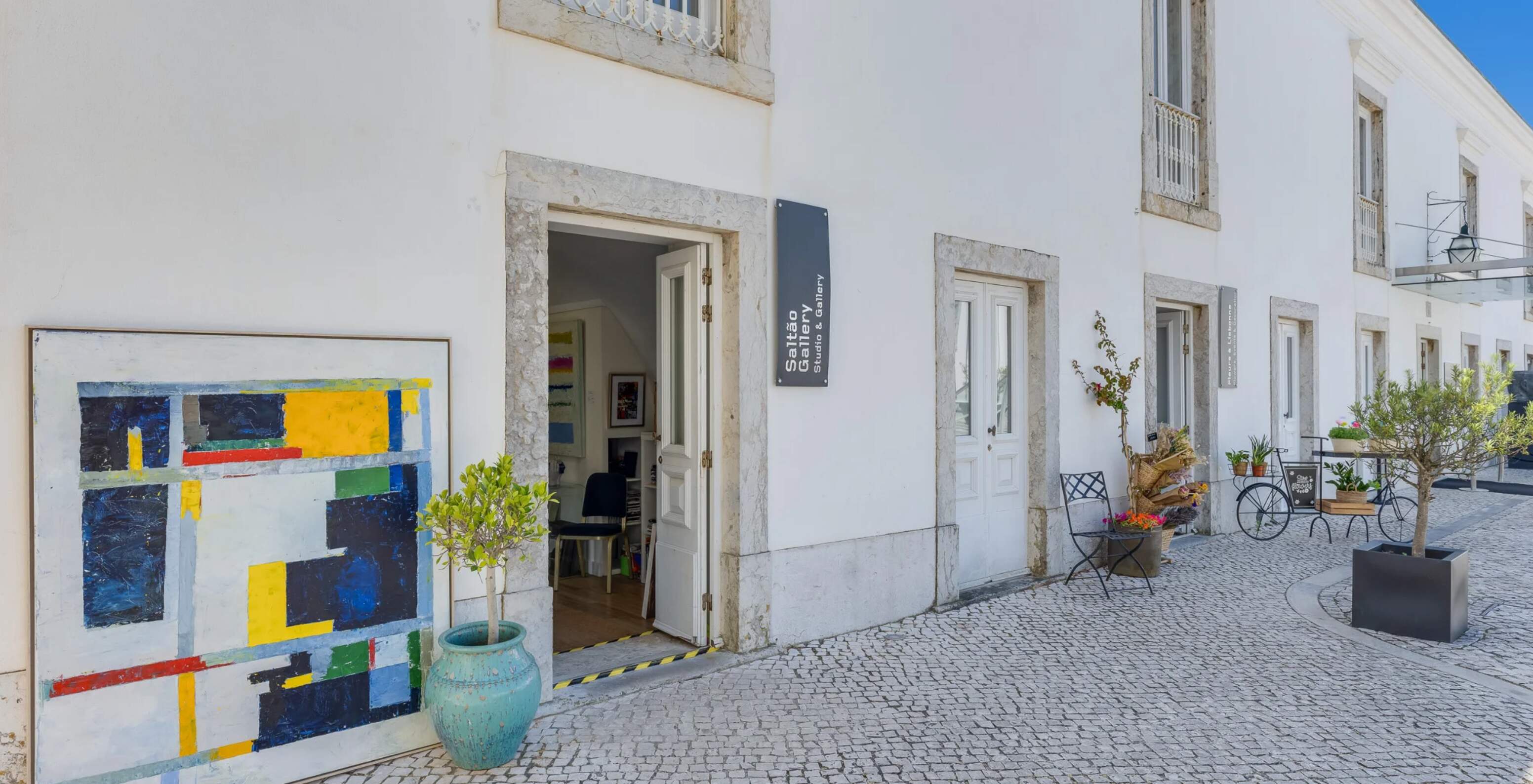 Galeria de arte junto ao Pestana Cidadela Cascais com fachada branca, quadro colorido e esplanada exterior