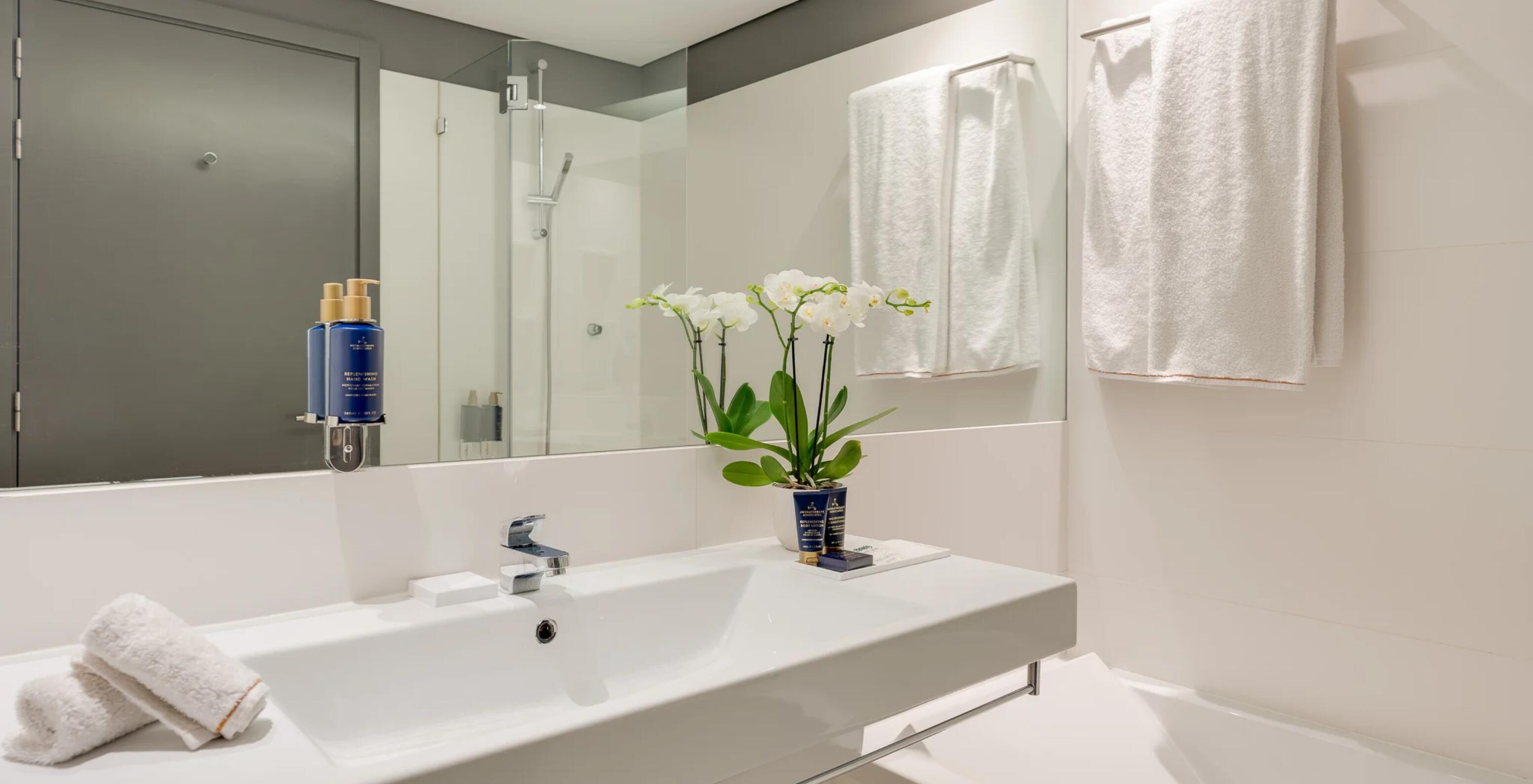 Hotel Pestana Cidadela Cascais com casa de banho moderna, lavatório branco, espelho amplo e toalhas brancas