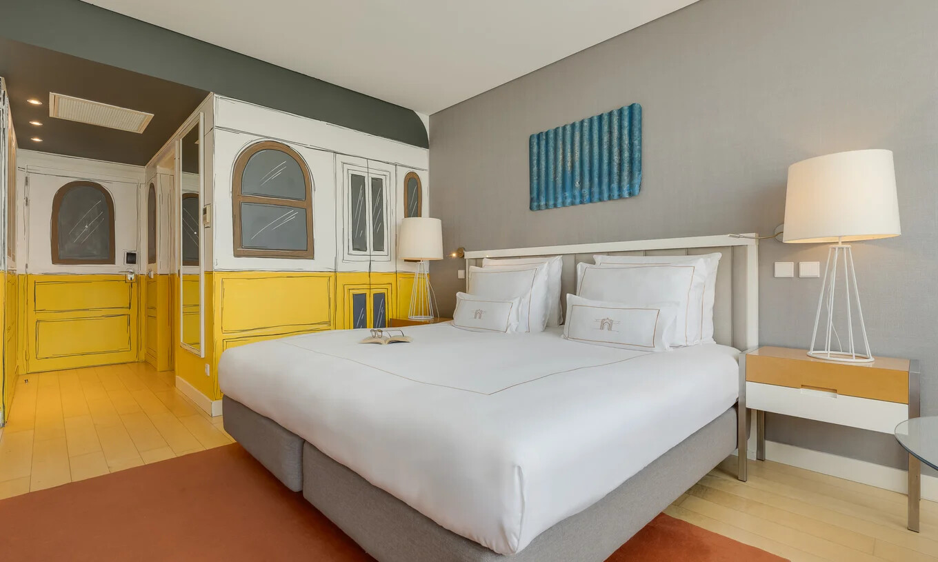 Quarto com cama de casal, paredes cinzentas, mesas laterais iluminadas e armário amarelo decorativo