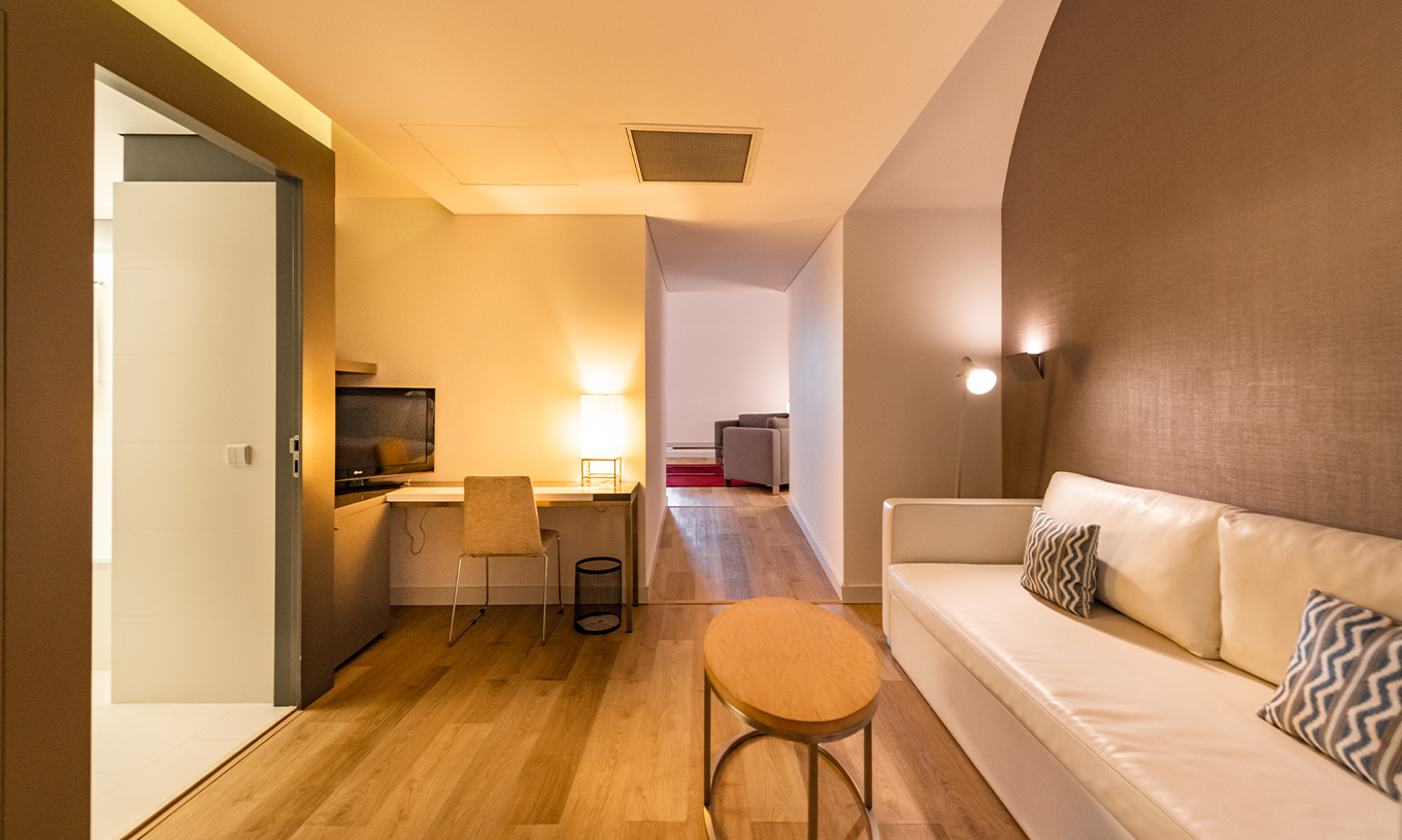 A Junior Suite Familiar do Pestana Cidadela Cascais tem uma sala com um sofá, uma mesa de apoio e uma secretária