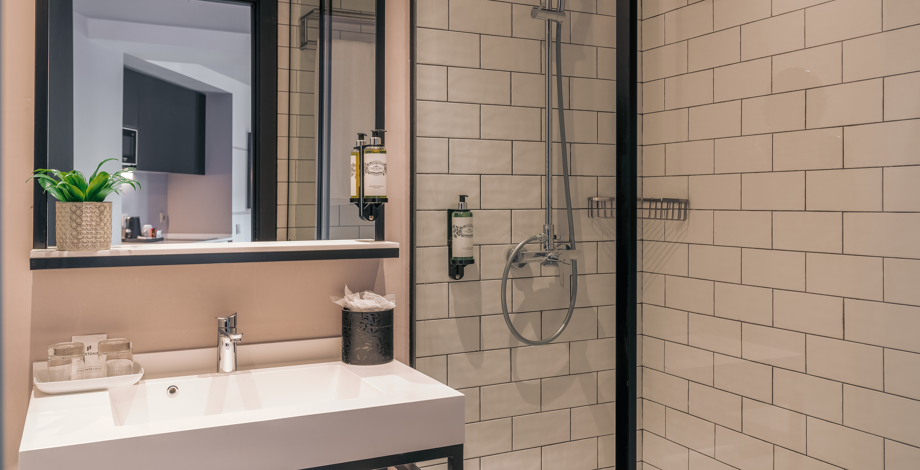 O Double Deluxe Studio do Pestana Lisboa Vintage tem um duche com portas de vidro e detalhes pretos, e um lavatório
