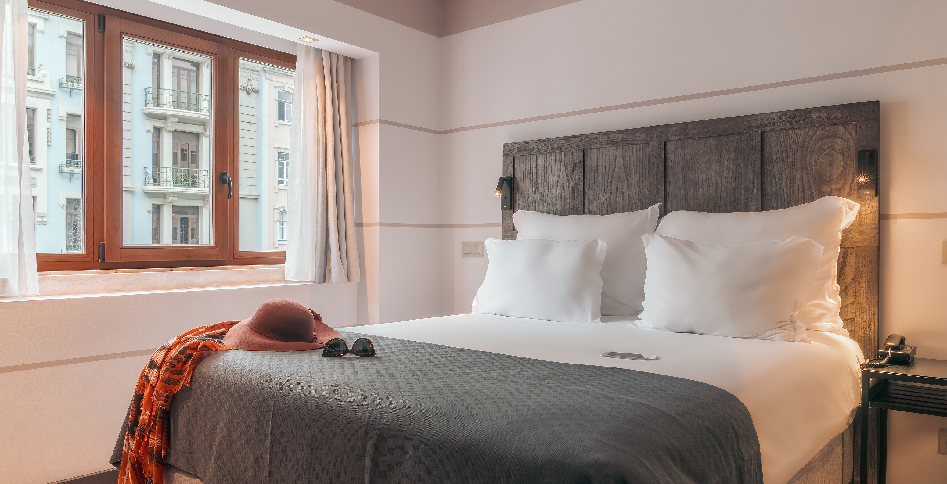 O Double Classic do Pestana Lisboa Vintage tem uma cama de casal com cabeceira e uma manda cinzentas e uma janela de madeira