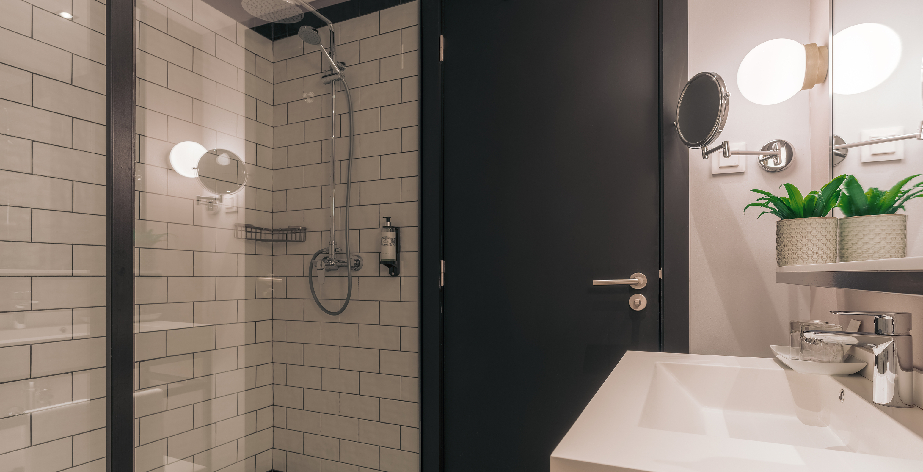 A Rooftop Junior Suite do Pestana Lisboa Vintage tem uma casa de banho com duche com portas de vidro e dois espelhos