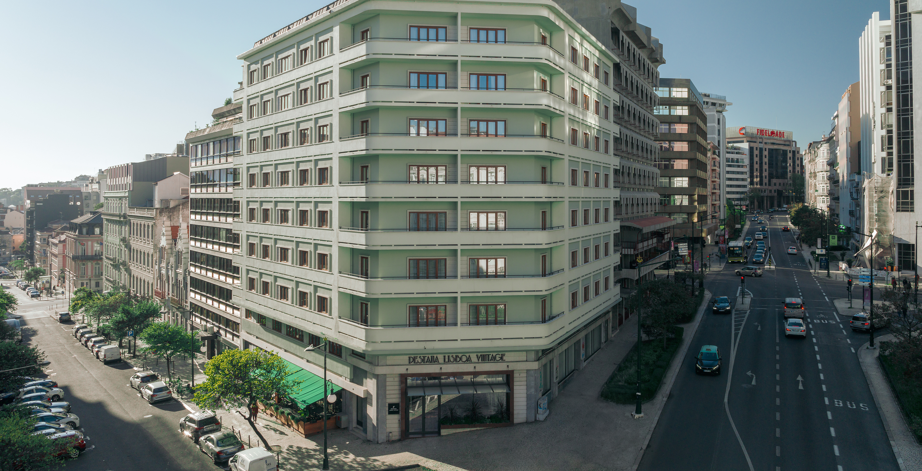 Vista exterior do edifício verde do Pestana Lisboa Vintage, as ruas nas laterais com árvores e carros na estrada