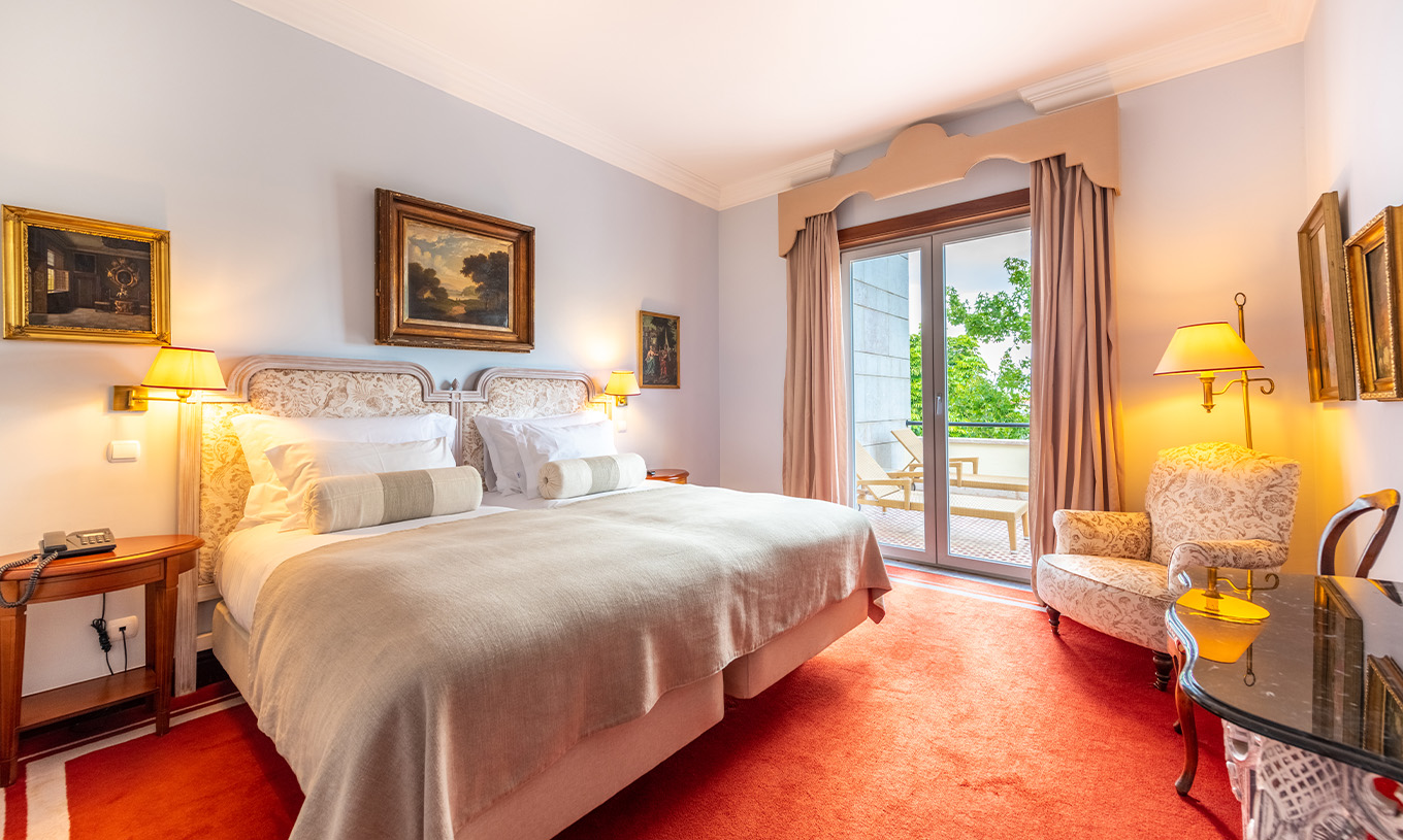 A Suite Collection do Pestana Palace Lisboa tem uma cama de casal, uma poltrona, secretária e uma janela com acesso ao jardim