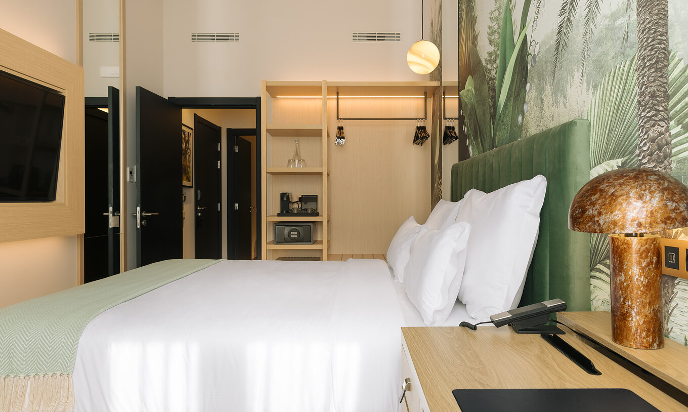 A Suite Familiar do Pestana Rua Augusta Lisboa tem uma cama de casal com televisão em frente e uma janela com cortinas