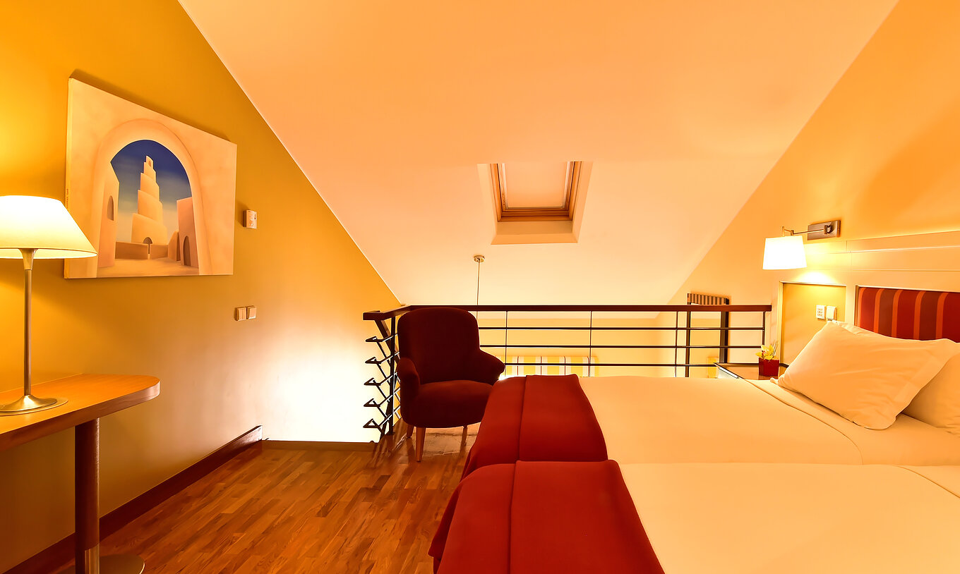 A Suite Mezzanine Familiar do Pestana Sintra Golf tem uma mezzanine com duas camas, uma cadeira, um quadro e uma mesa