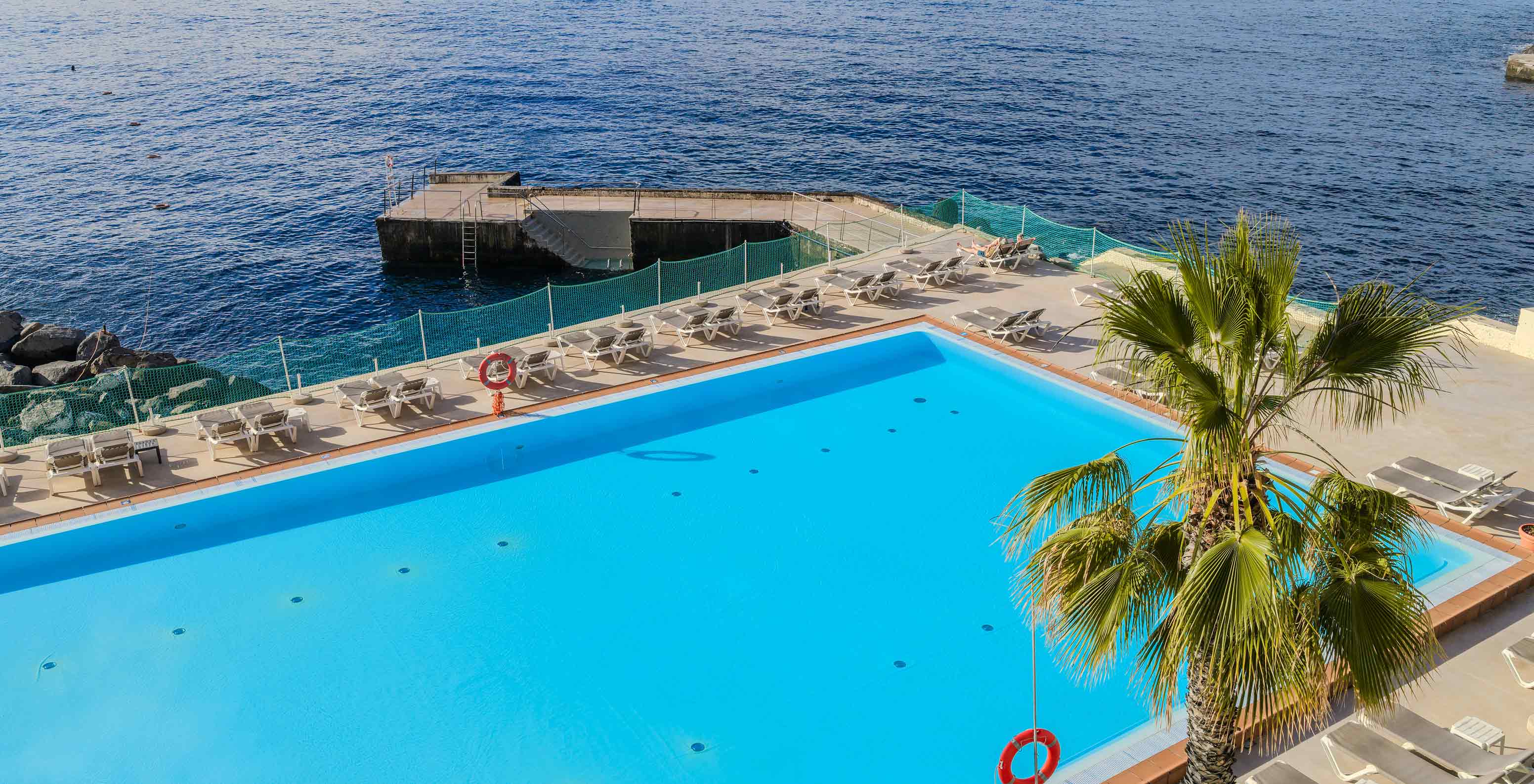 Piscina exterior junto ao mar perto do Pestana Carlton Madeira, Hotel 5 Estrelas na Madeira com espreguiçadeiras