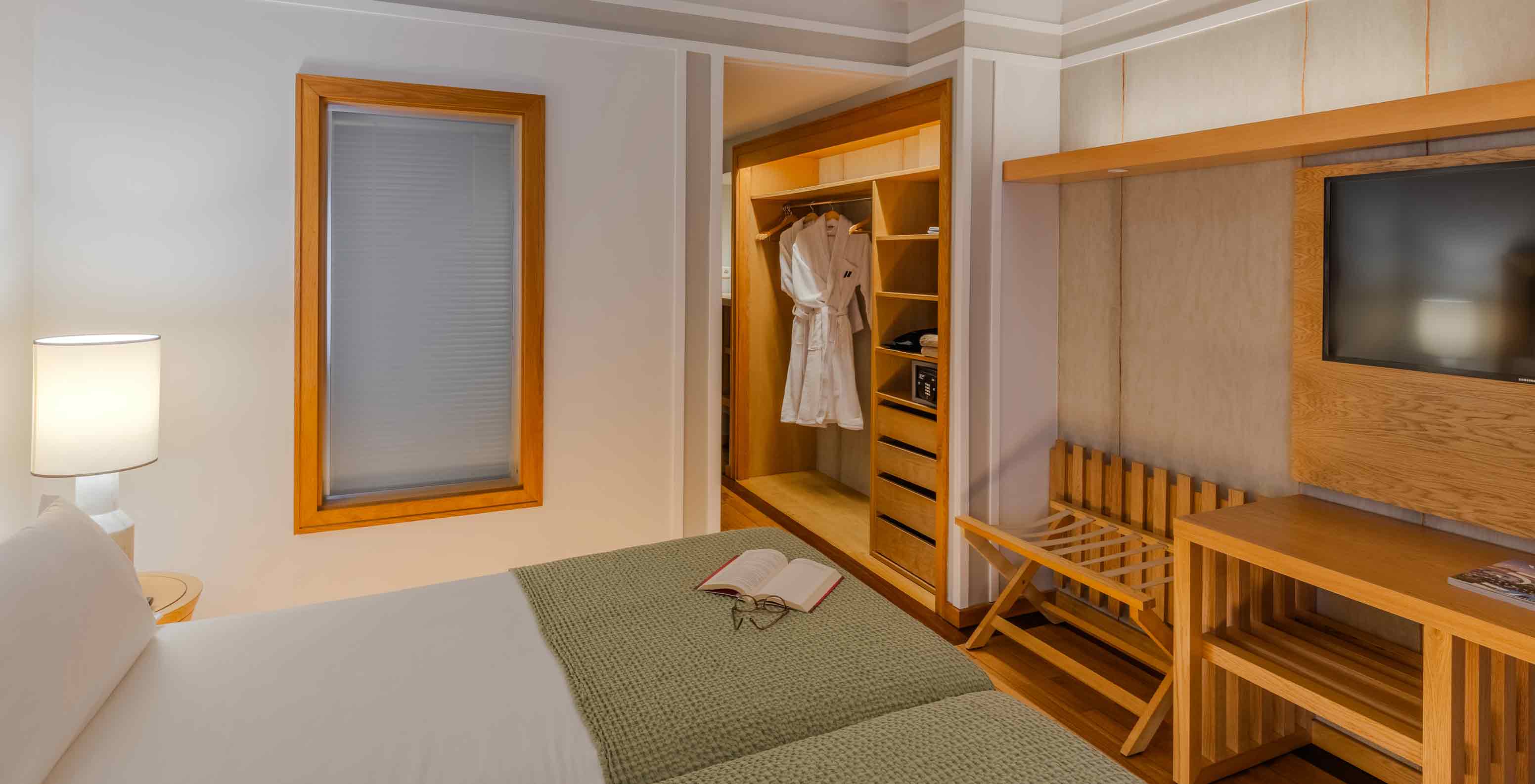 Quarto Clássico no Pestana Carlton Madeira com cama ampla, televisão embutida e roupeiro em madeira iluminado