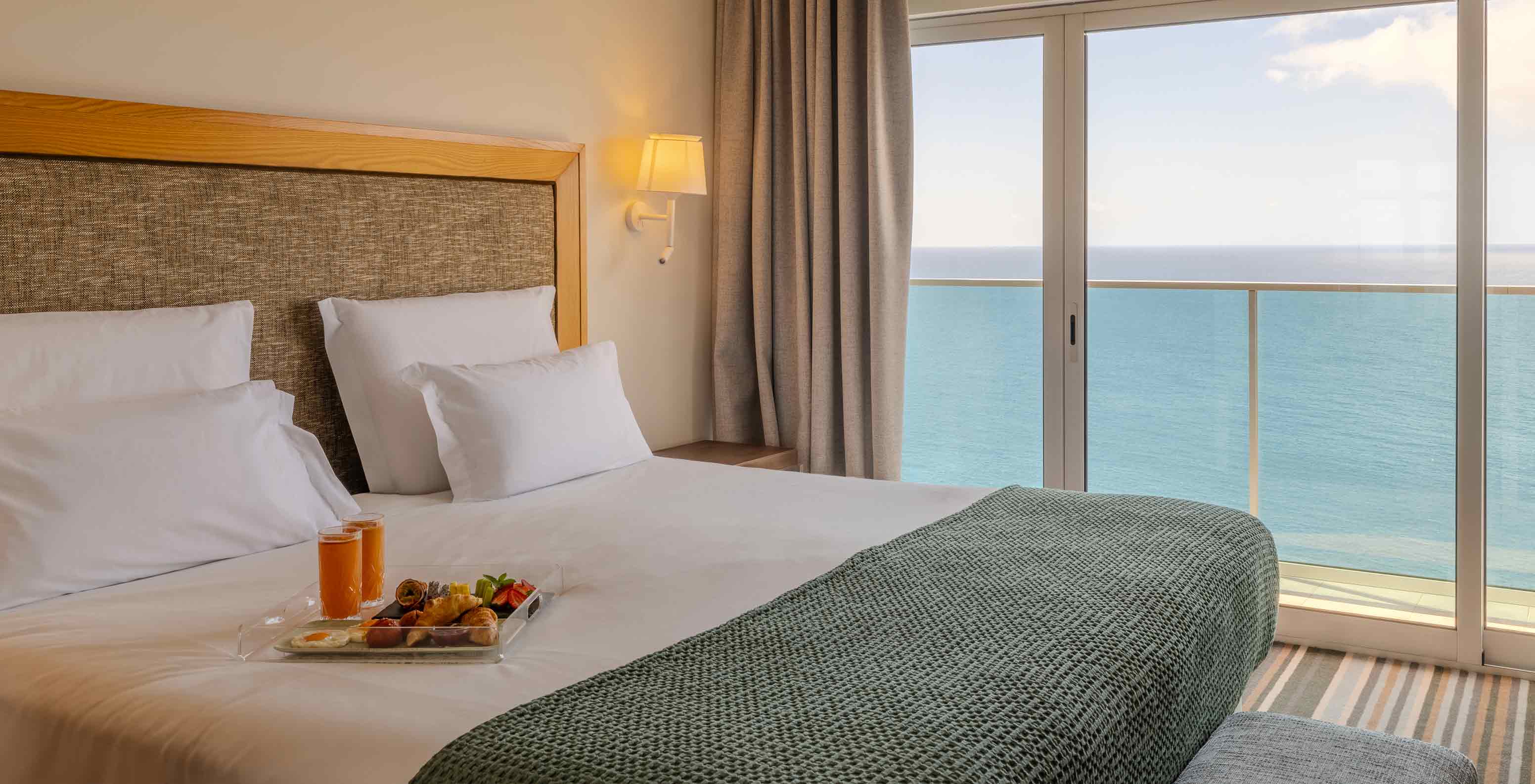 Suite Júnior Superior no Pestana Carlton Madeira com cama ampla e varanda voltada para o oceano azul