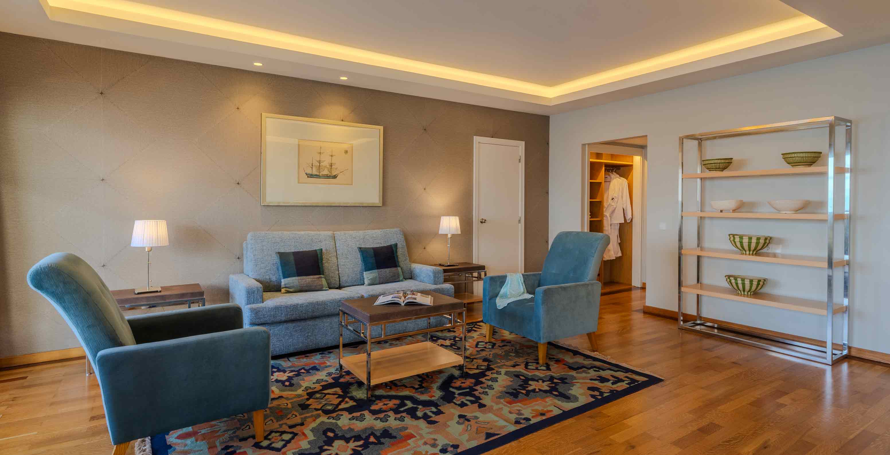 Suite Presidencial no Pestana Carlton Madeira com sala ampla, sofá cinzento, poltronas azuis e iluminação suave