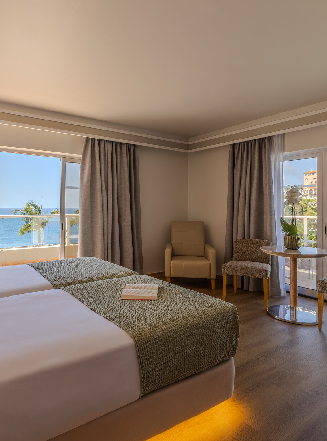 Suite Júnior do Pestana Carlton Madeira com camas individuais, área de estar e varanda com vista mar