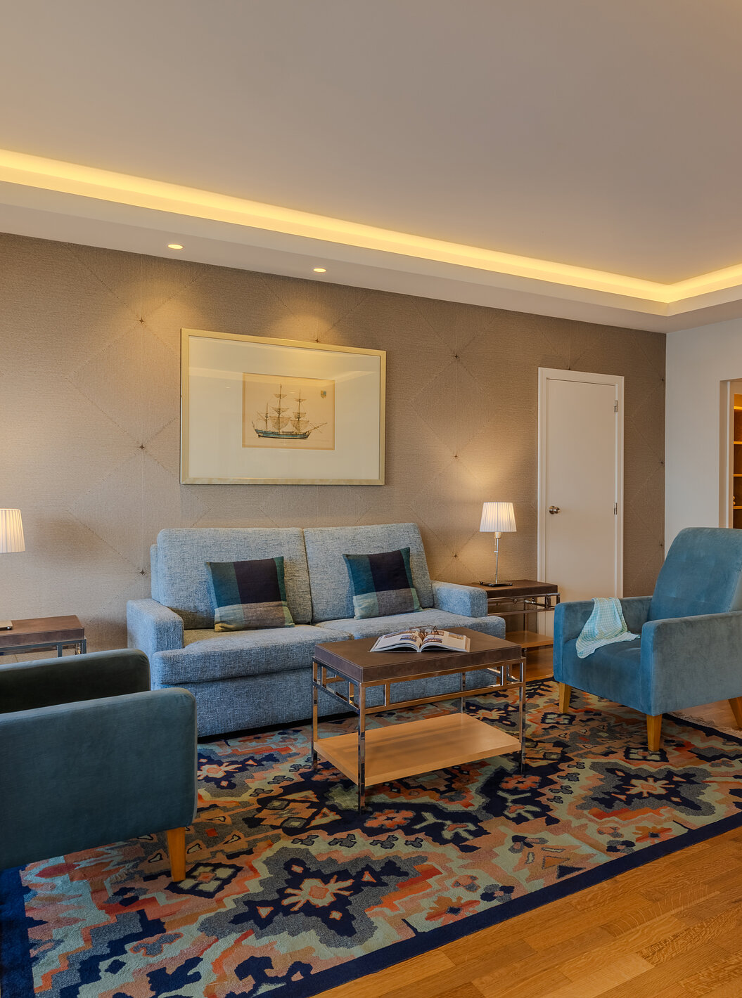 Suíte Presidencial no Pestana Carlton Madeira com sofá cinza, poltronas azuis e mesa sobre tapete estampado