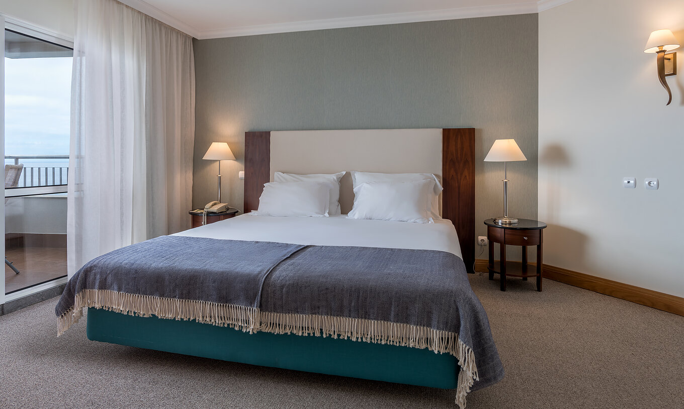O quarto Twin Superior Vista Mar do Pestana Grand tem cama de casal com mesa de cabeceira e candeeiros