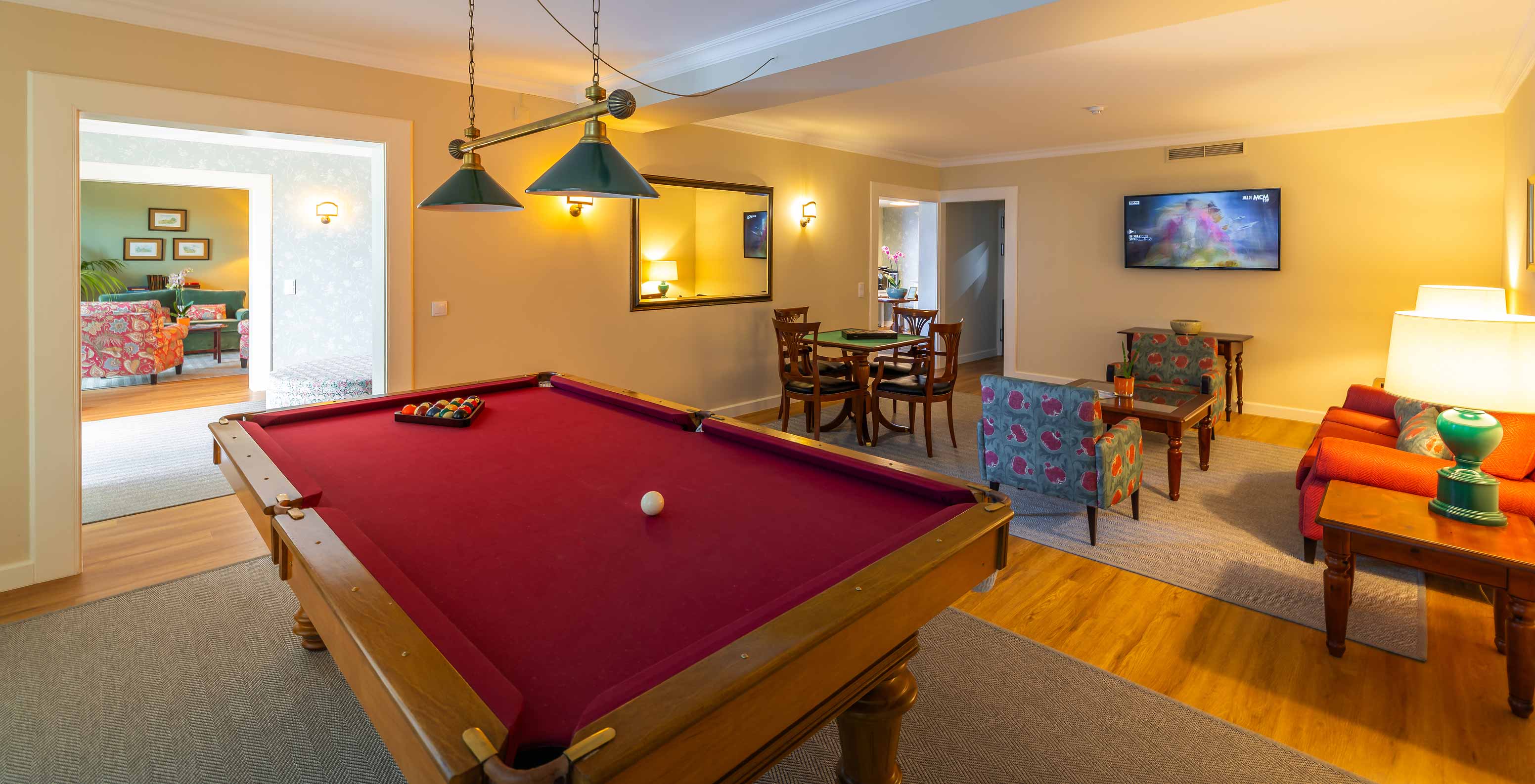 Sala de jogos do Pestana Quinta Perestrello com mesa para jogos de cartas, um sofá e uma mesa de bilhar 