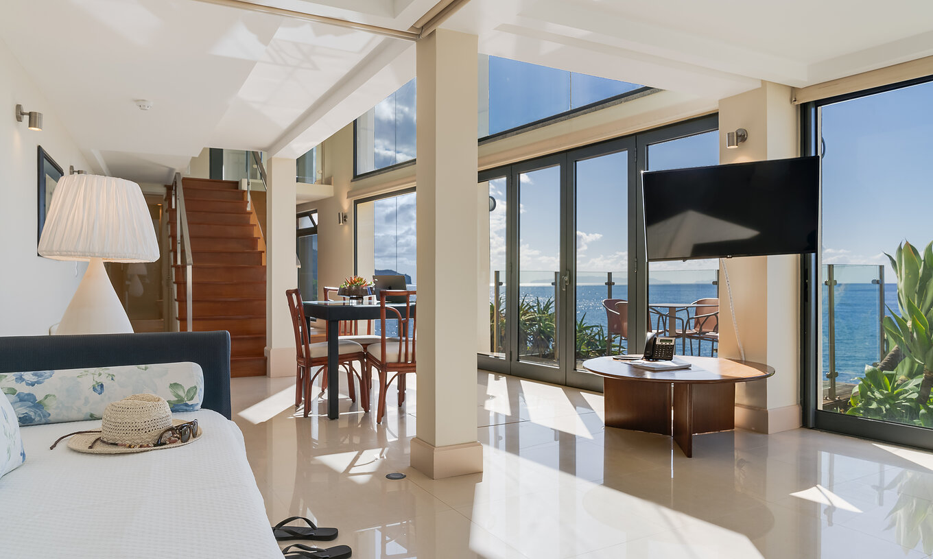 A Suite Duplex Vista Mar do Pestana Vila Lido Madeira tem uma sala ampla com vista para o sal, com sofá e mesa de refeições