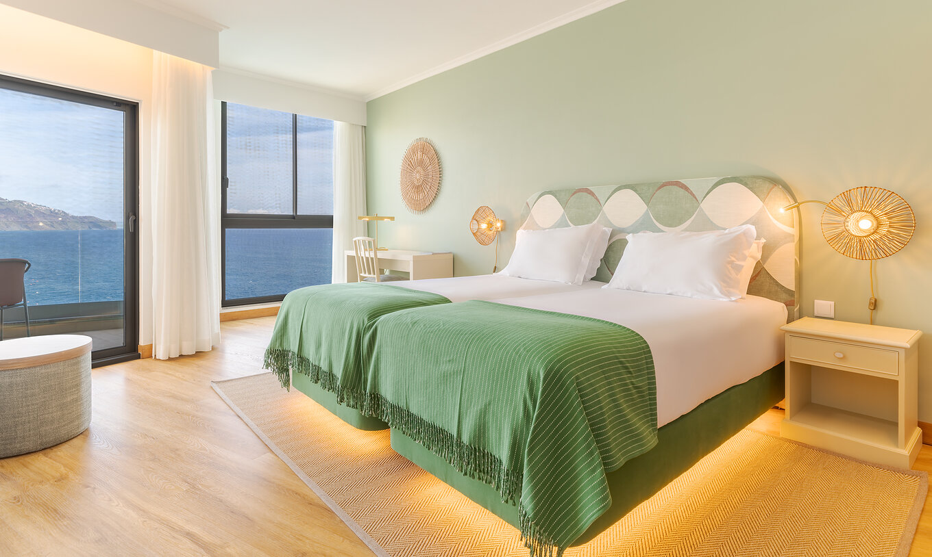 O Superior Vista Mar do Pestana Vila Lido Madeira tem tons verdes, duas camas, uma secretária com cadeira e uma varanda