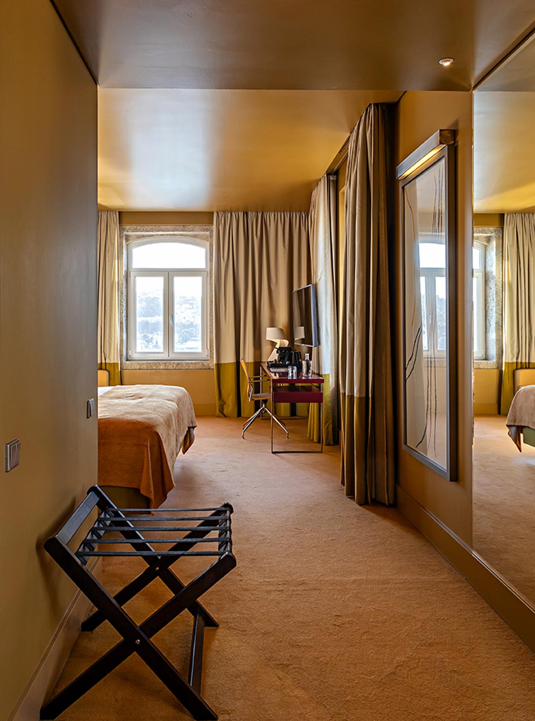 Quarto Deluxe Grand View do Pestana Palácio do Freixo, com decoração elegante, cama dupla, janelas amplas e vista luminosa sobre o rio