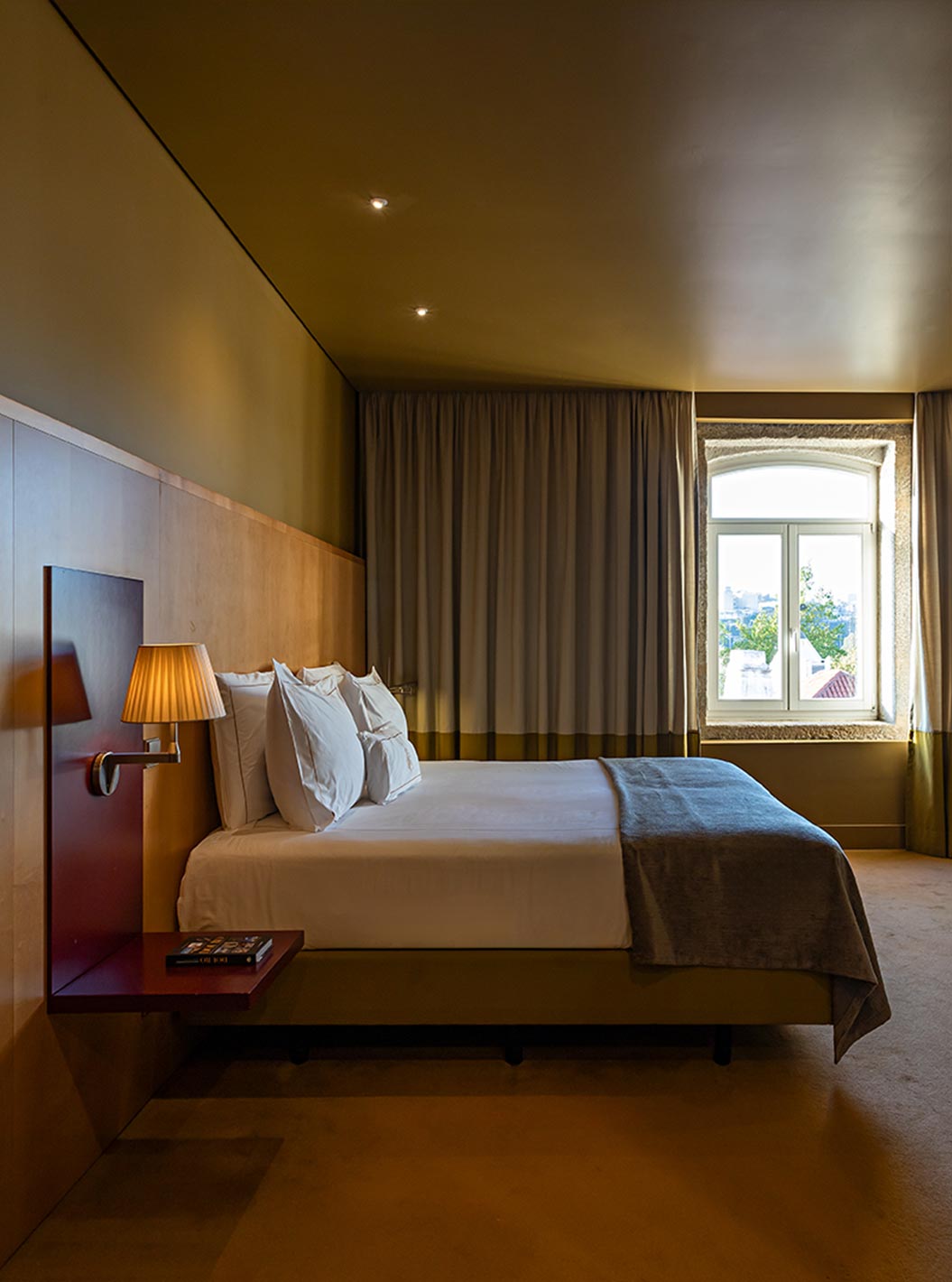 Quarto Executivo do Pestana Palácio do Freixo com cama dupla, iluminação suave, cortinas fechadas e janela com vista para o exterior