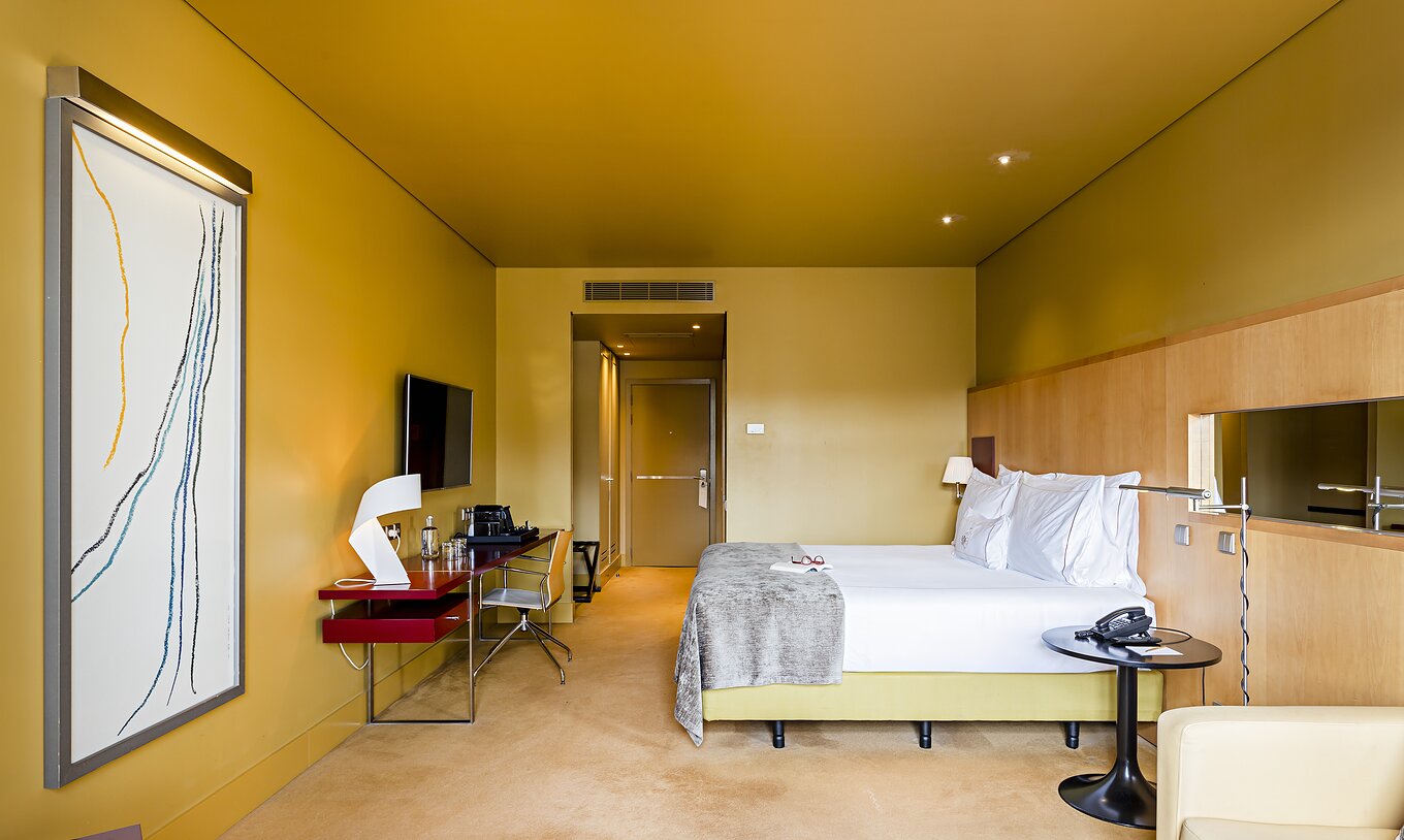 O Superior do Pestana Palácio do Freixo tem uma cama de casal com colcha cinzenta e uma secretária