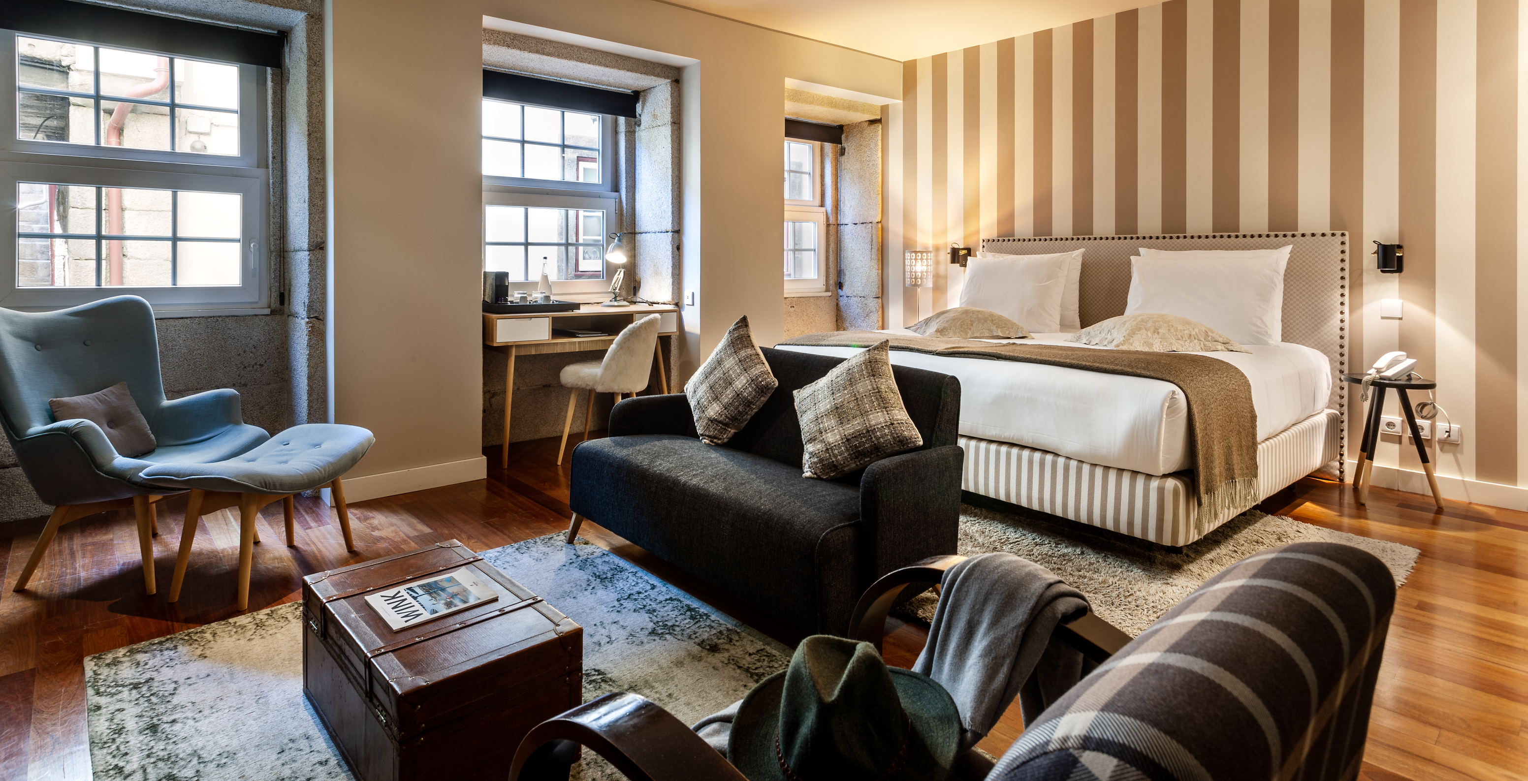 A Heritage Suite do Pestana Vintage Porto tem uma cama de casal, um sofá, dois cadeirões e papel de parede às riscas